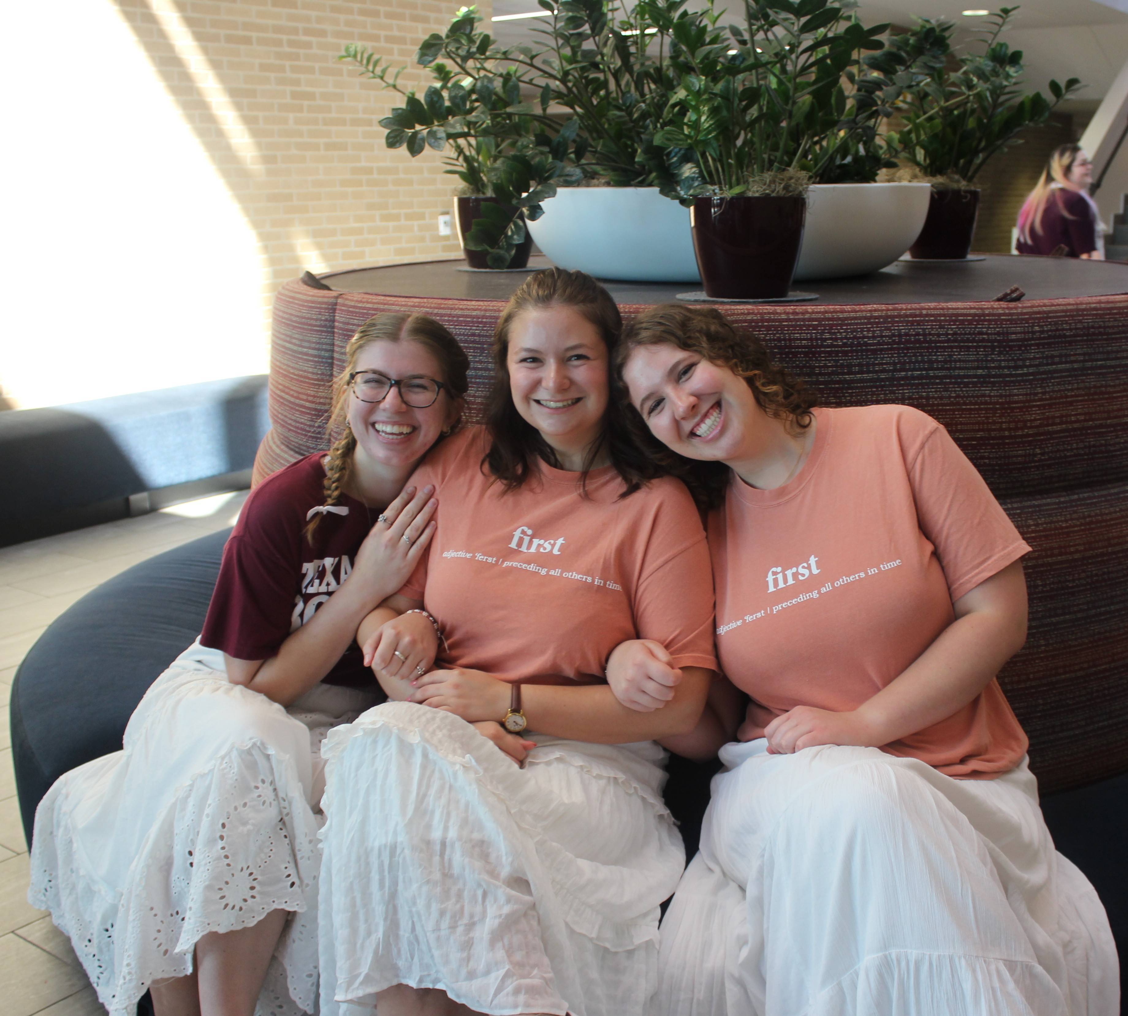 Three women posing in peach colored first gen shirts