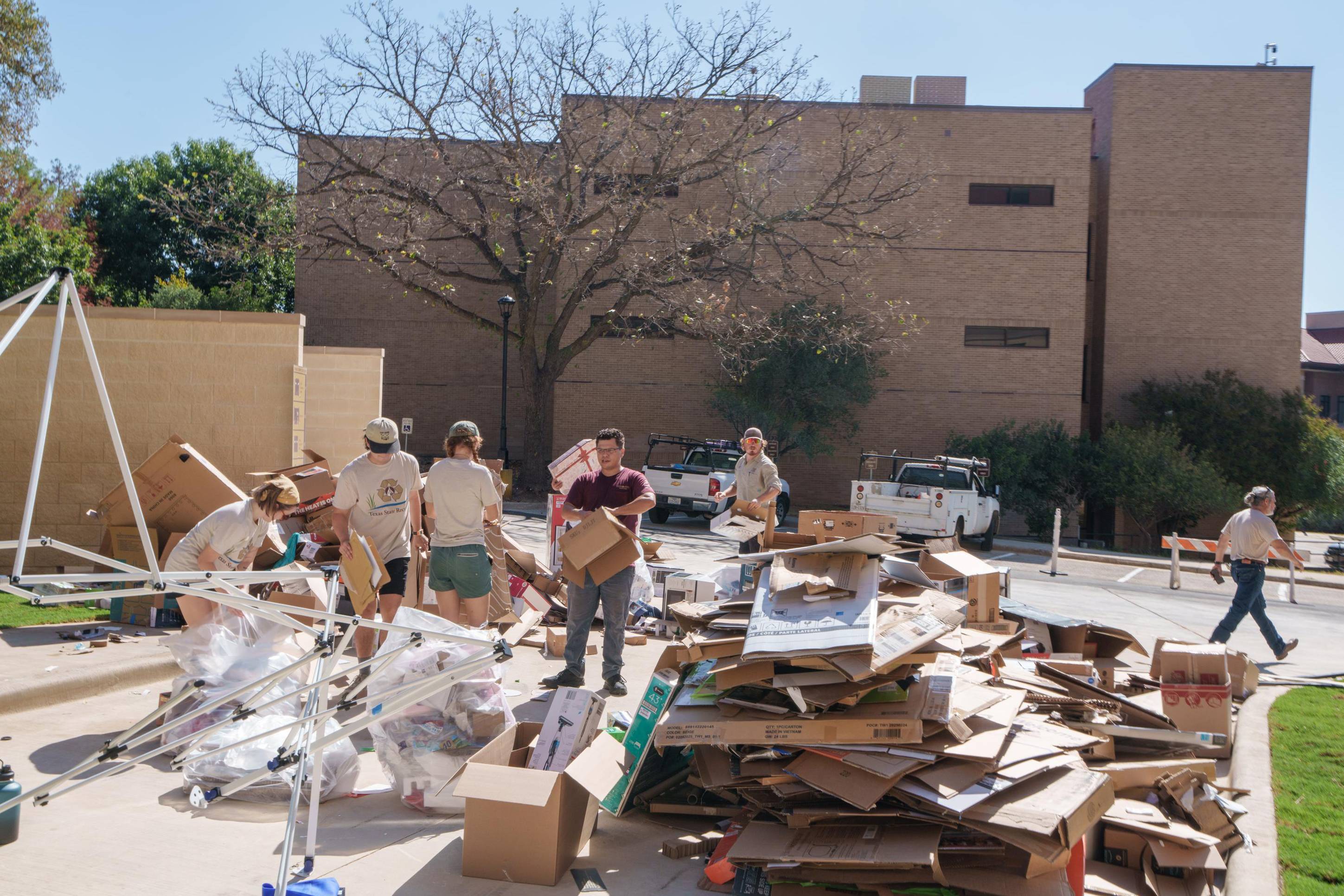 people work to break down large pile of cardboard boxes
