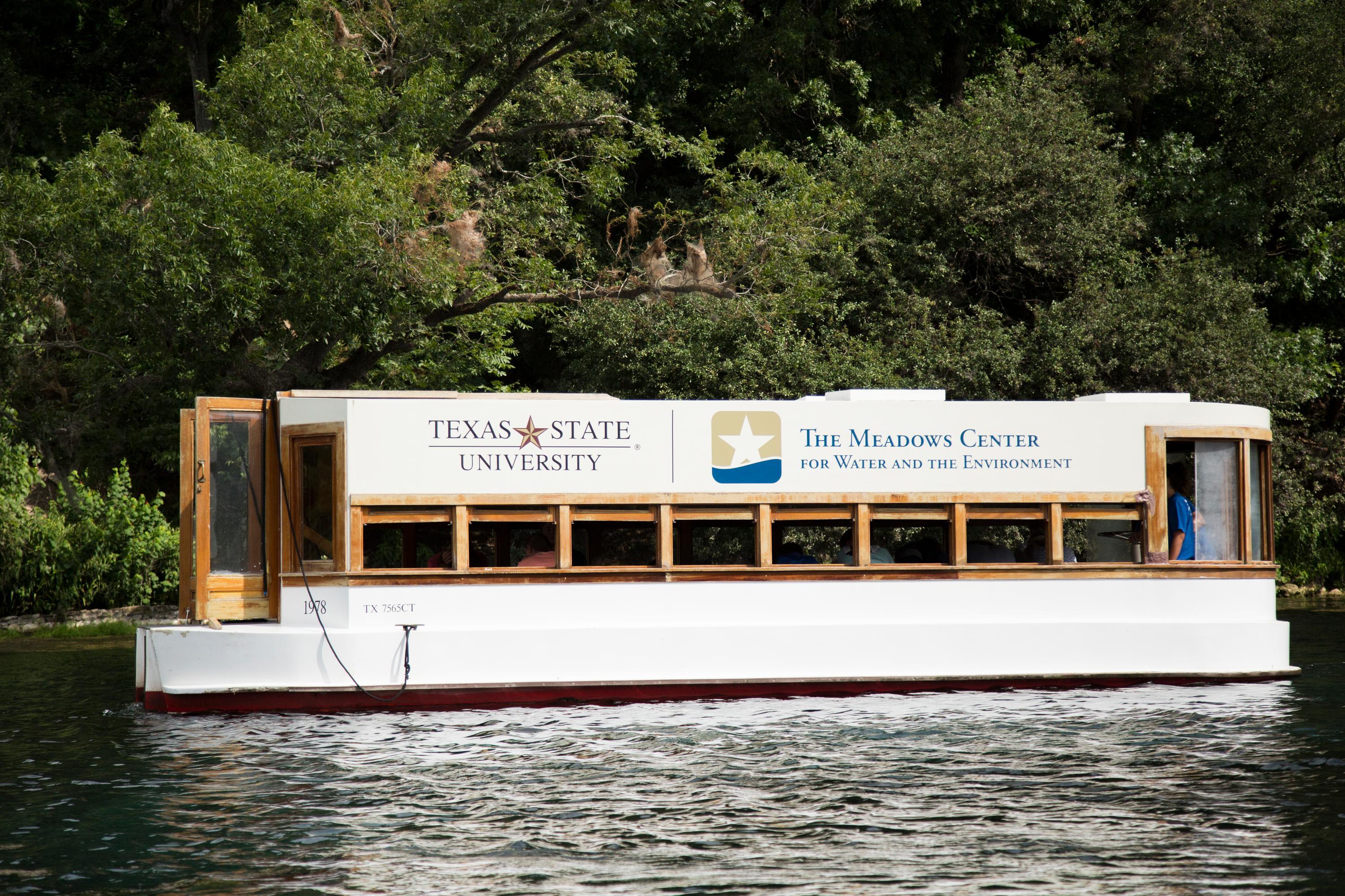 glass bottom boat with the meadows center and texas state signage on the side