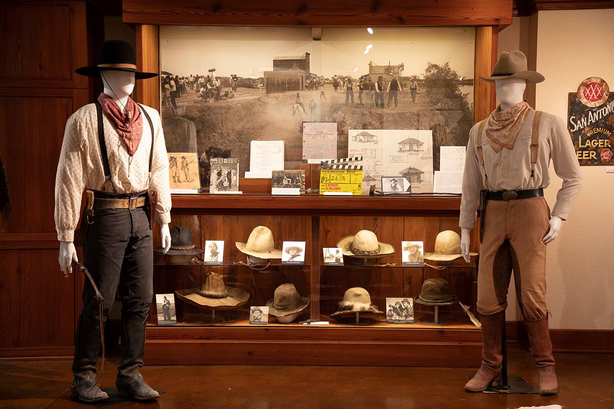 Two mannequins wearing costumes from Lonesome Dove are on both sides of a glass case with other memorabilia from the show.