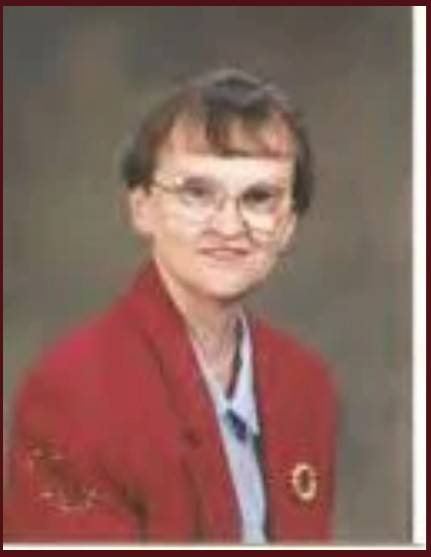 Dr. Muir wearing glasses and red blazer in studio portrait