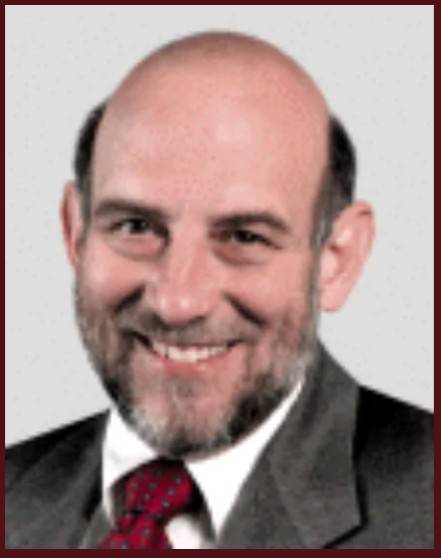 Dr. Stanley Israel in suit and red tie against neutral background