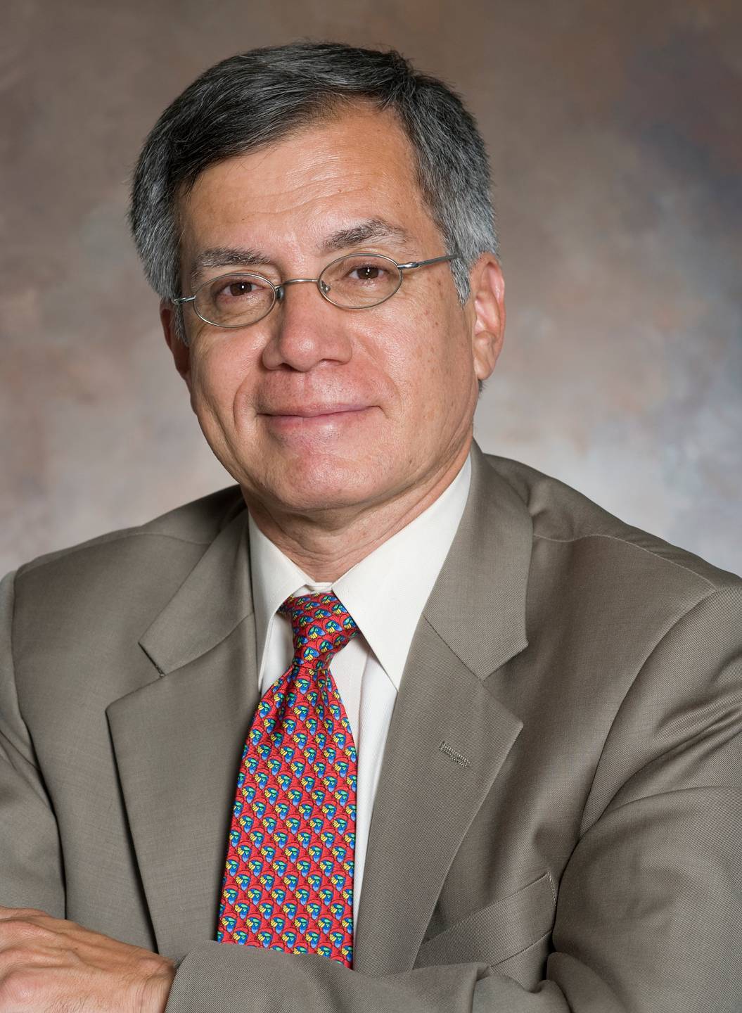 Dr. Flores in suit with patterned tie against neutral background
