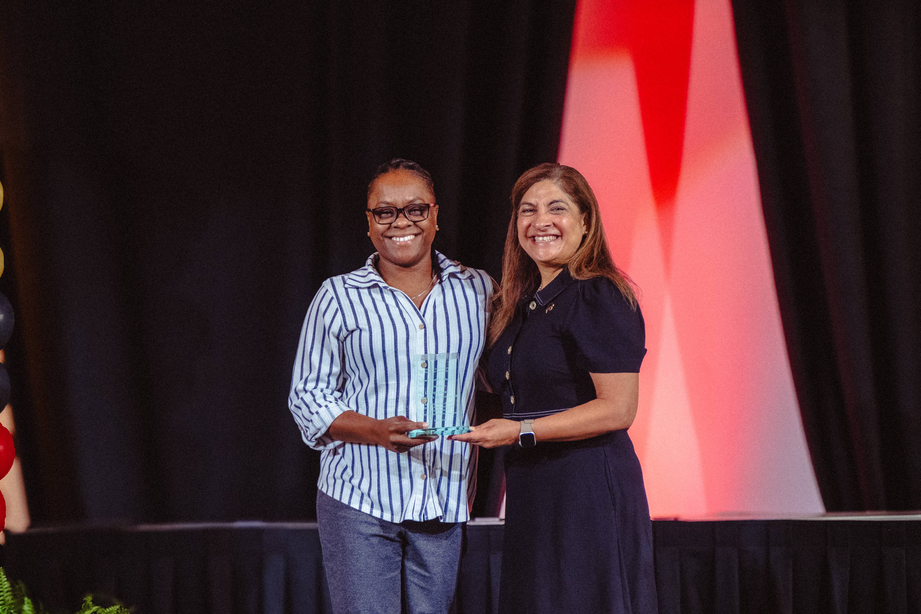 LaToya Howell and Dr. Cynthia L. Hernandez Hold an award on stage 
