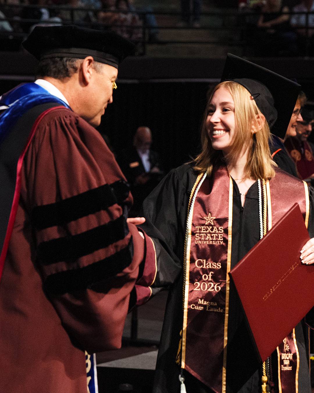 Student shaking hands with President Damphousse at commencement