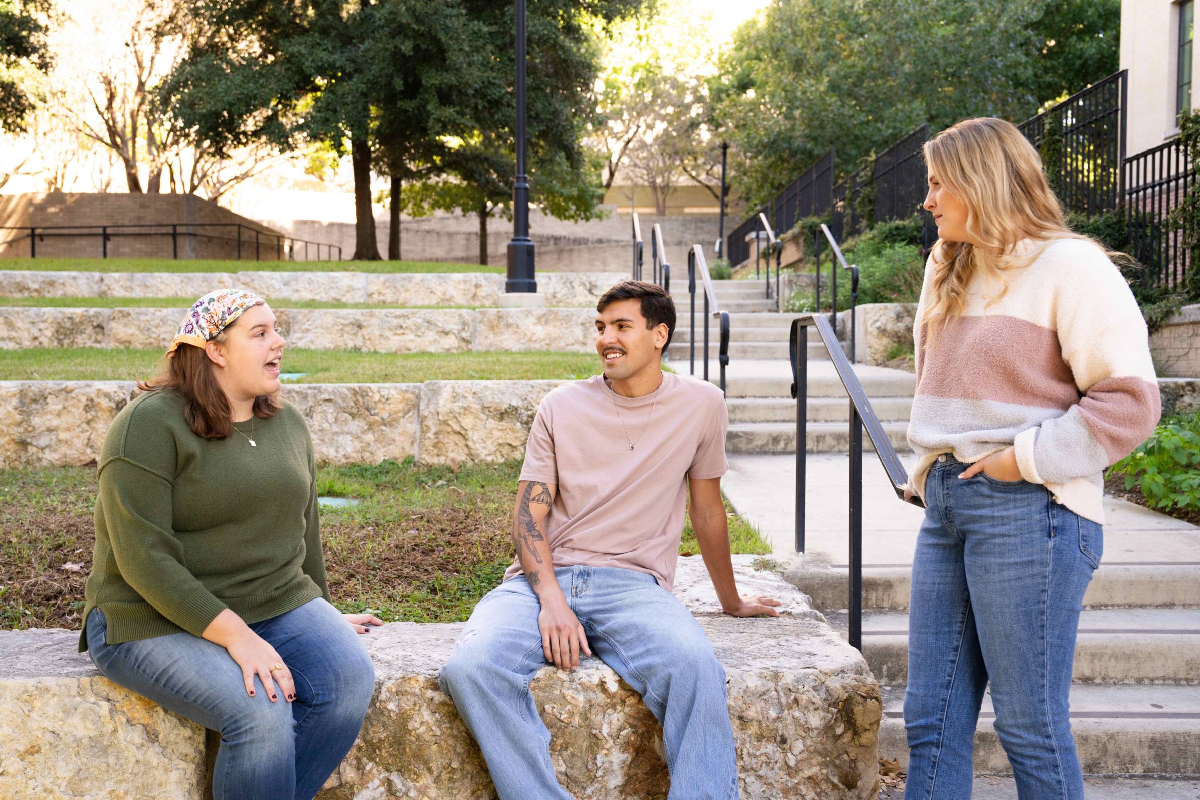 three people talking and smiling on campus