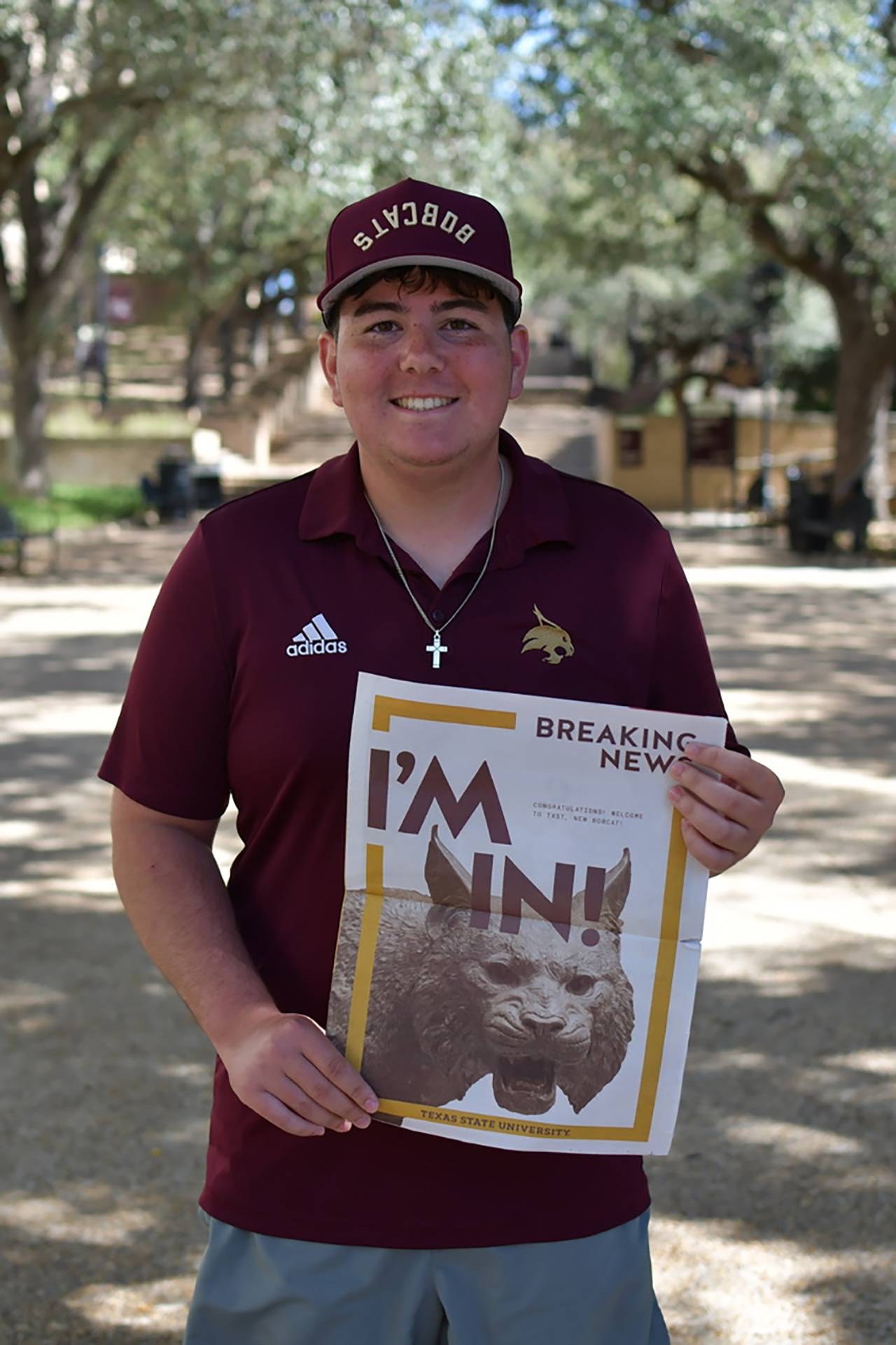 man smiling while holding up newspaper that reads "I'm in!"