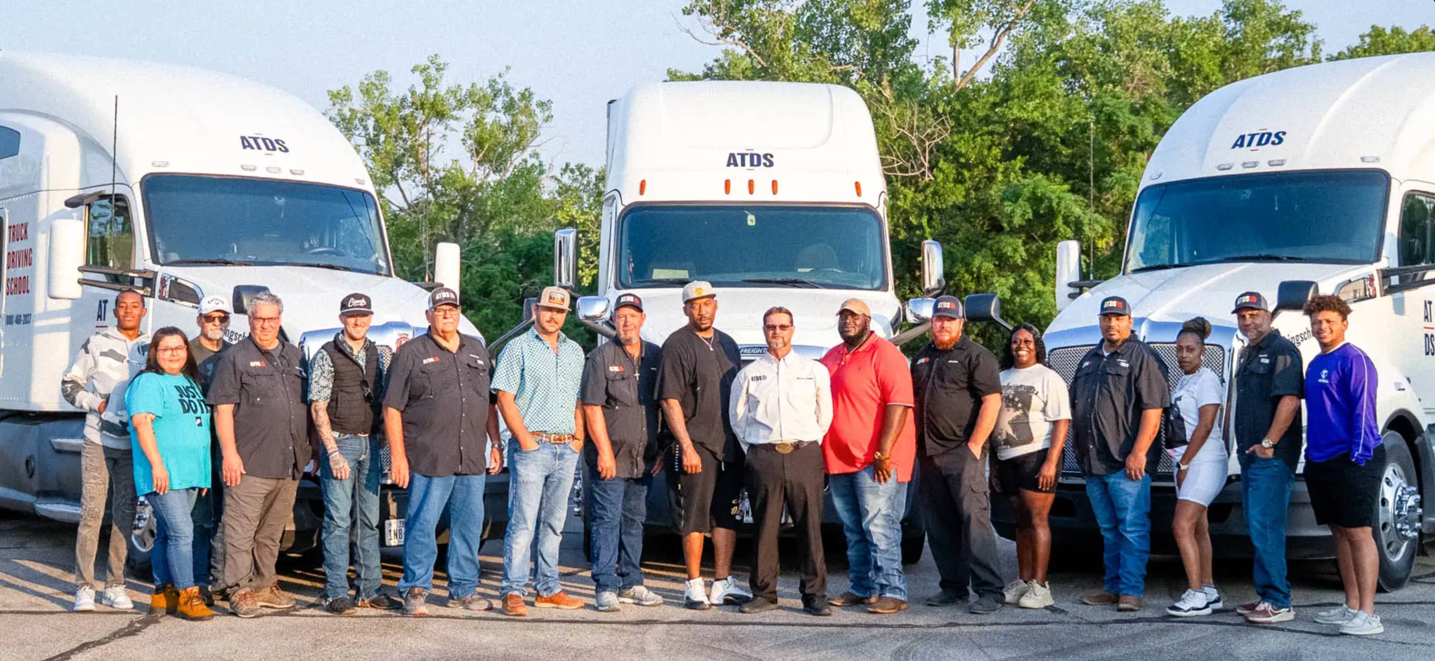 a group of people standing in front of 3 parked 18 wheel trucks