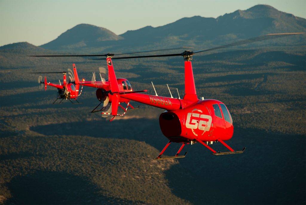 three red helicopters hover in the sky