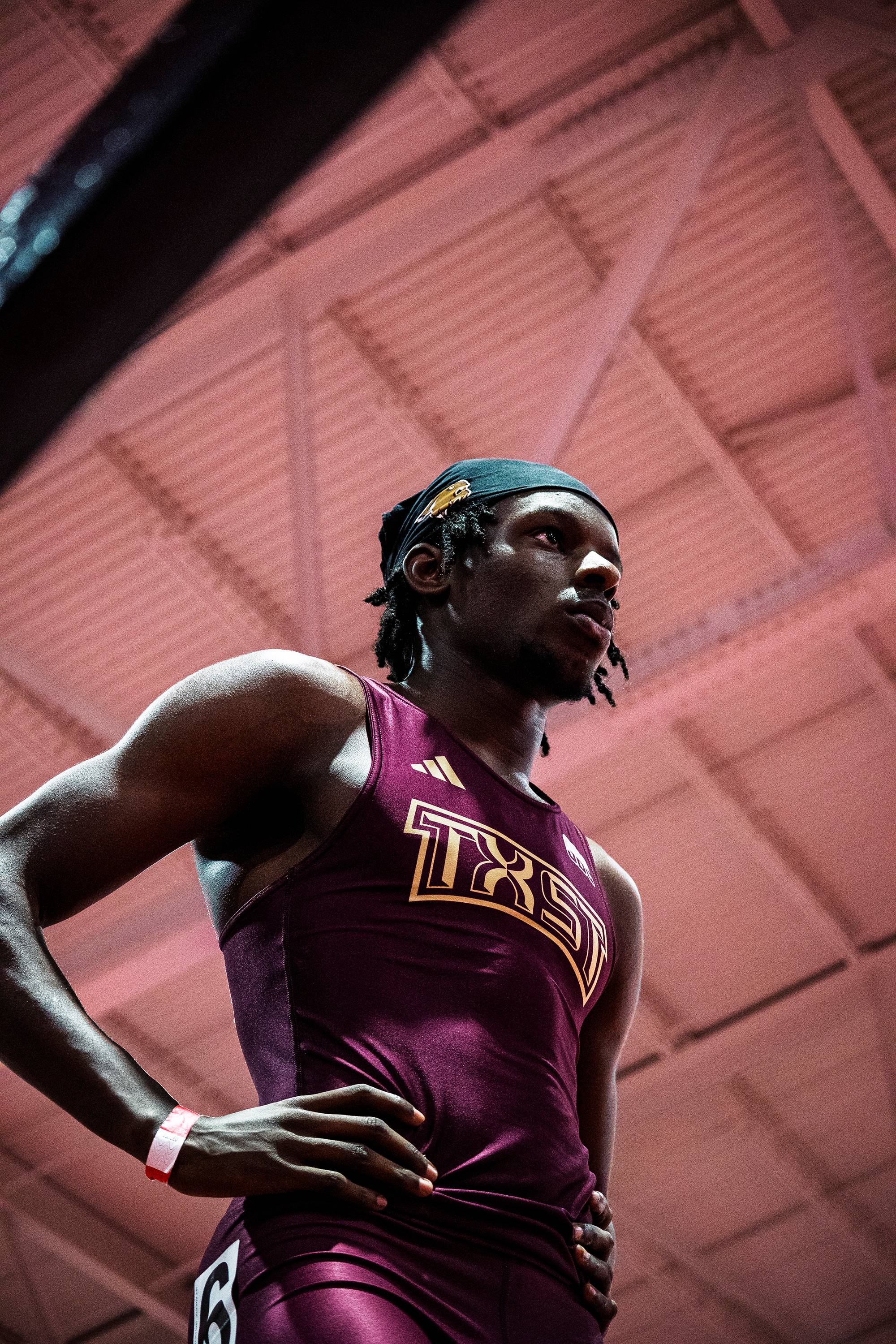 Ja’Shaun Lloyd stands in a gym wearing a maroon tank top with TXST in gold on it.