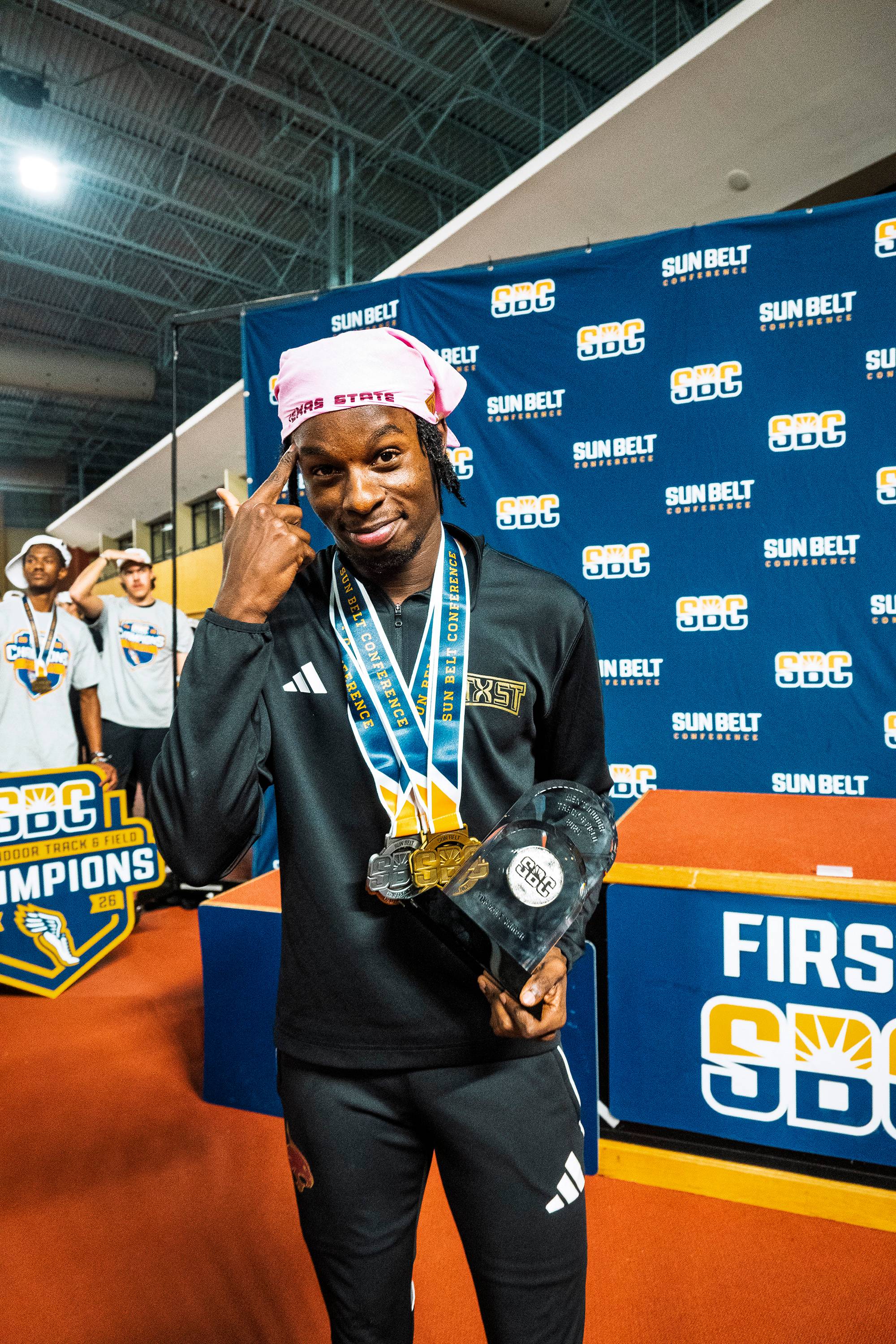  Ja’Shaun Lloyd wearing gold and silver medals and holding a trophy.