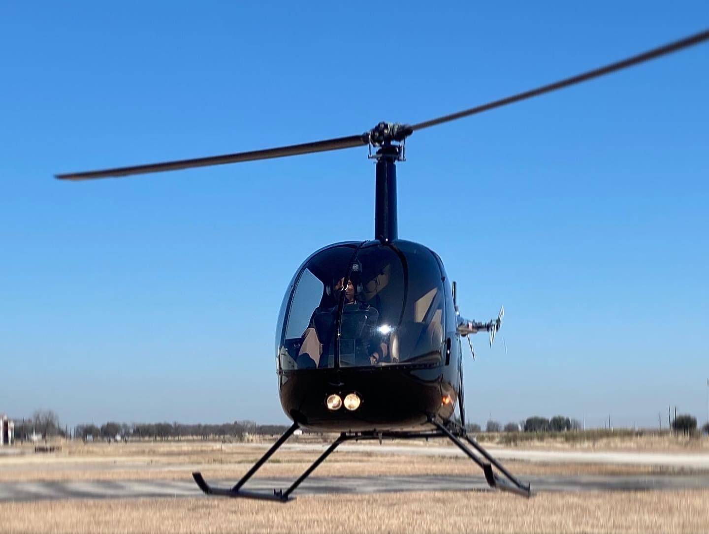 a black helicopter sits on the tarmac