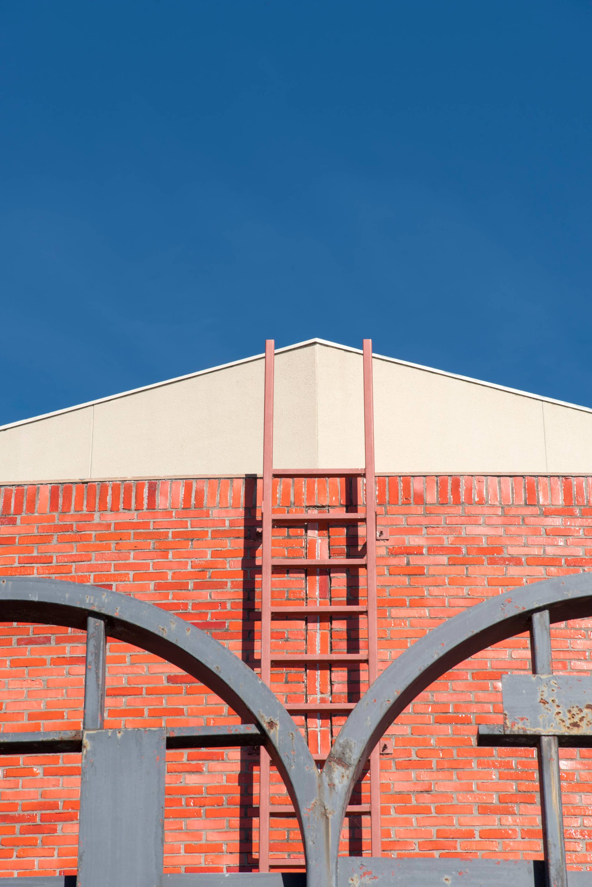 An aerial view looking down at the distinctive, circular red-tiled roof and red brick structure of the Theatre Center at Texas State University.