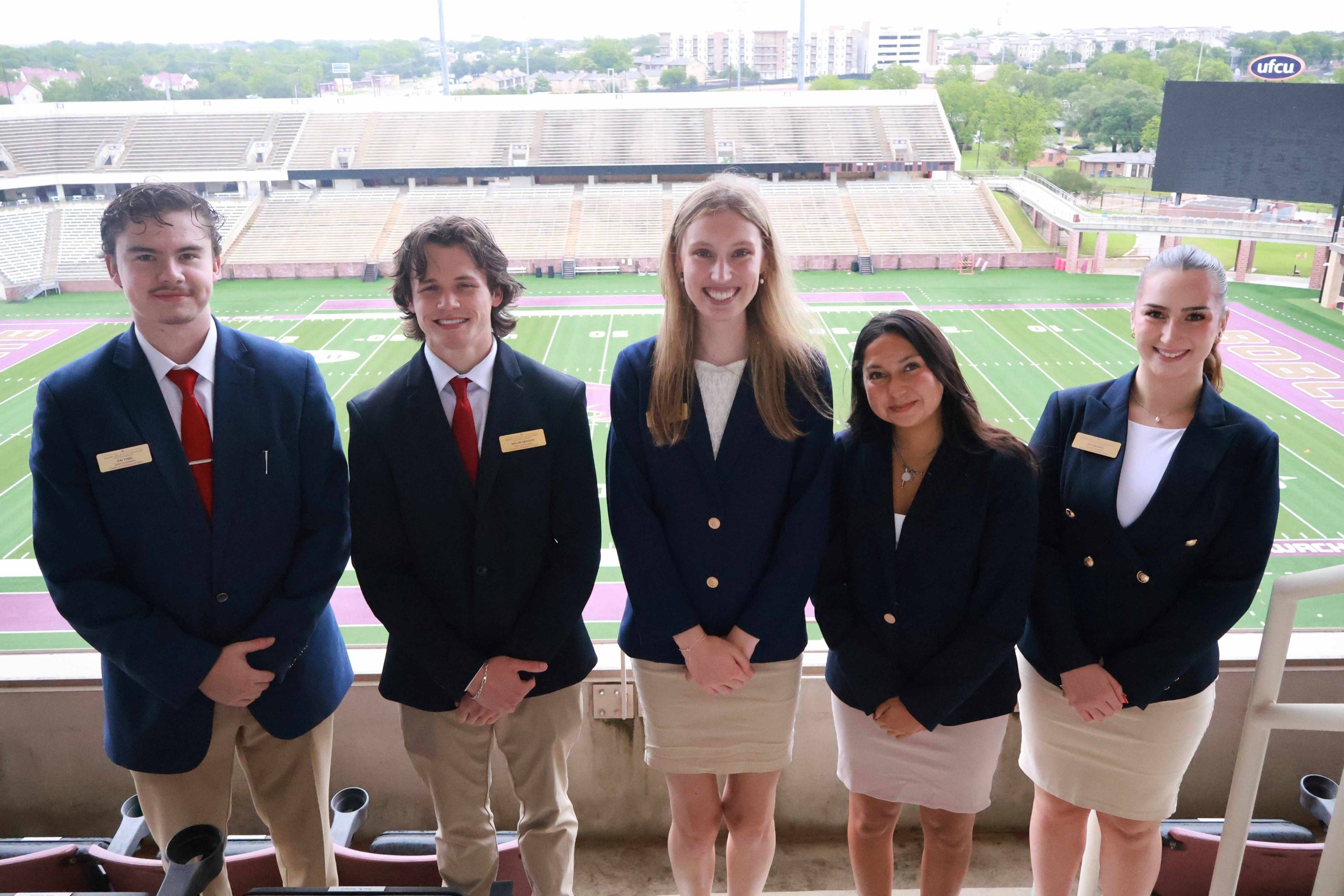five sales ambassadors posing for a photo at the football stadium