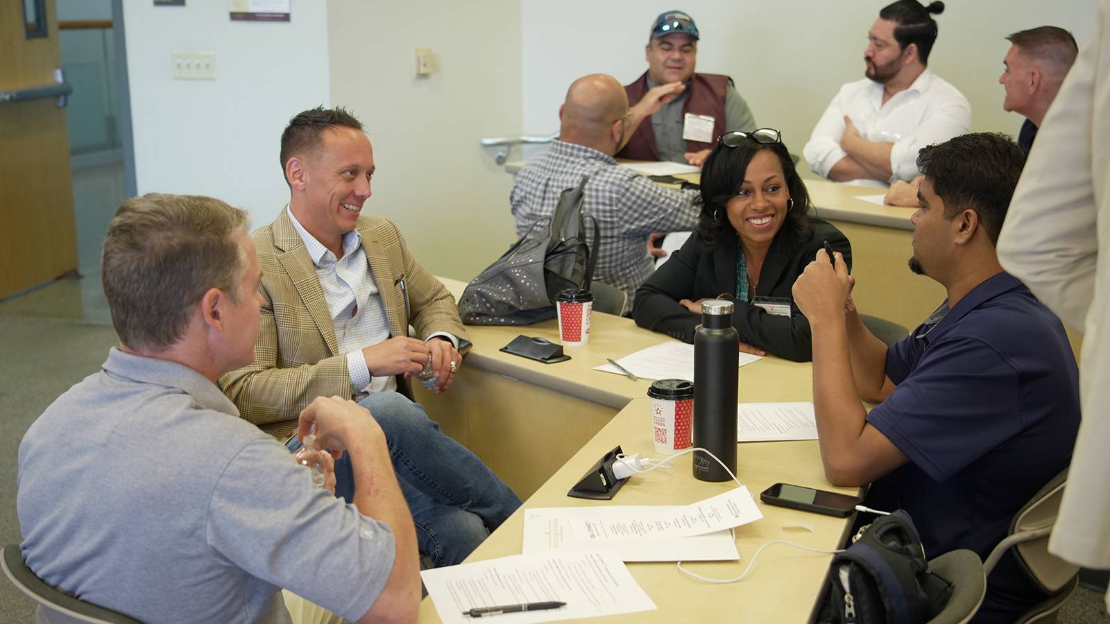 Eight adult college students talking in groups in classroom setting