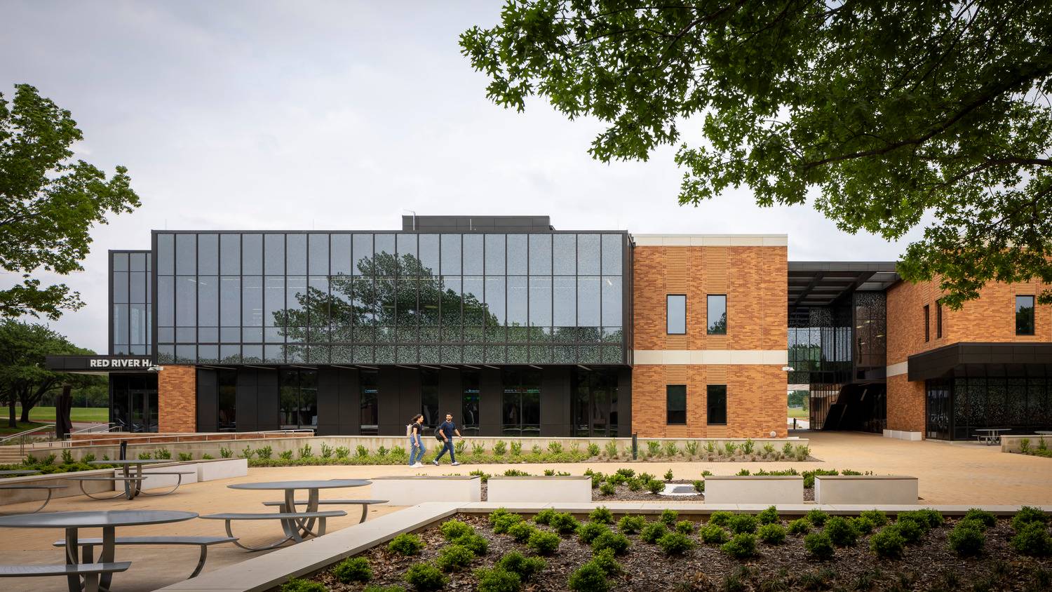 brick exterior of college campus with picnic tables and trees