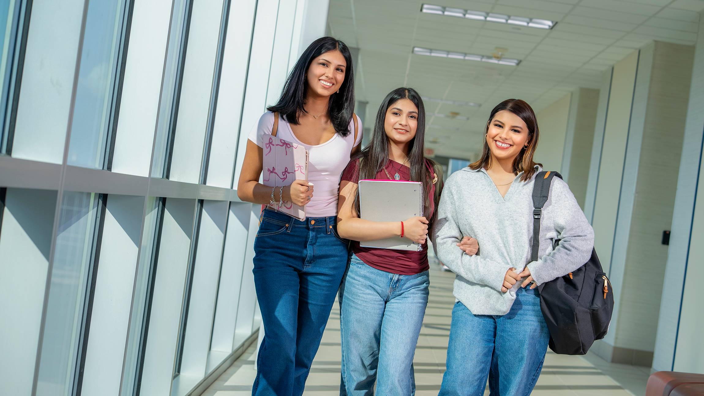 smiling students pose while holding binders