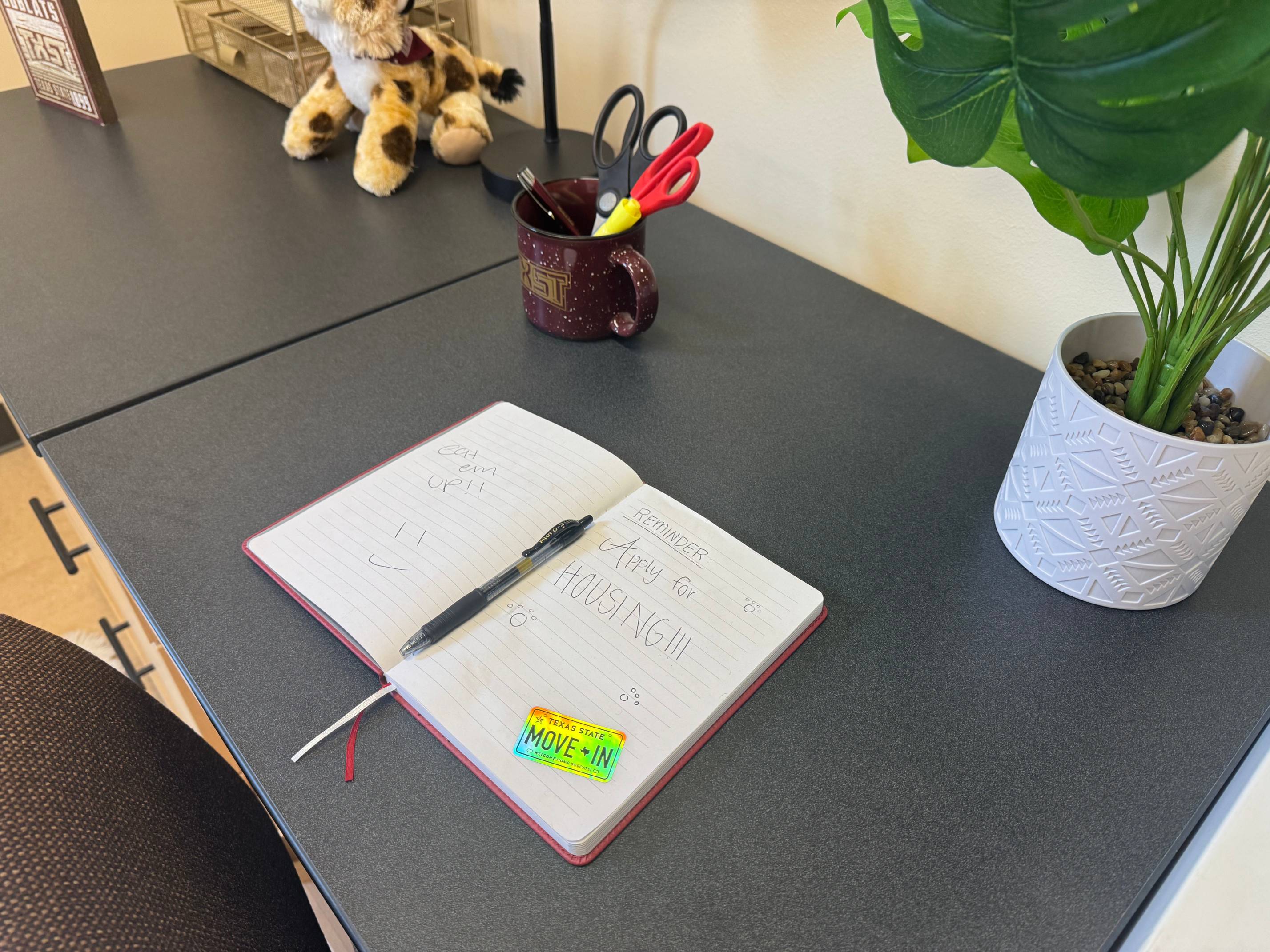 Notebook sitting on a desk reminding students to sign up for housing