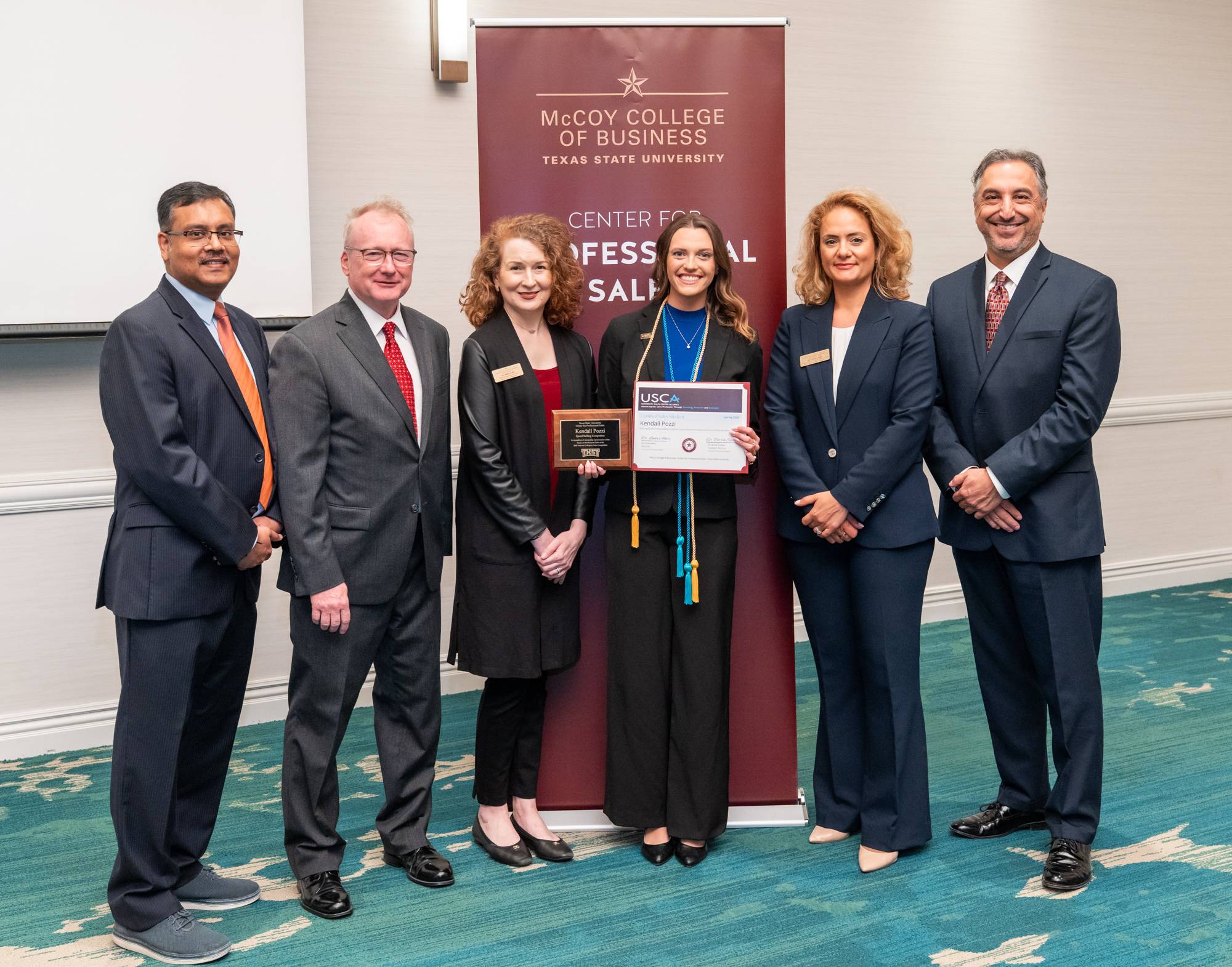 sales professors with sales student receiving a certificate
