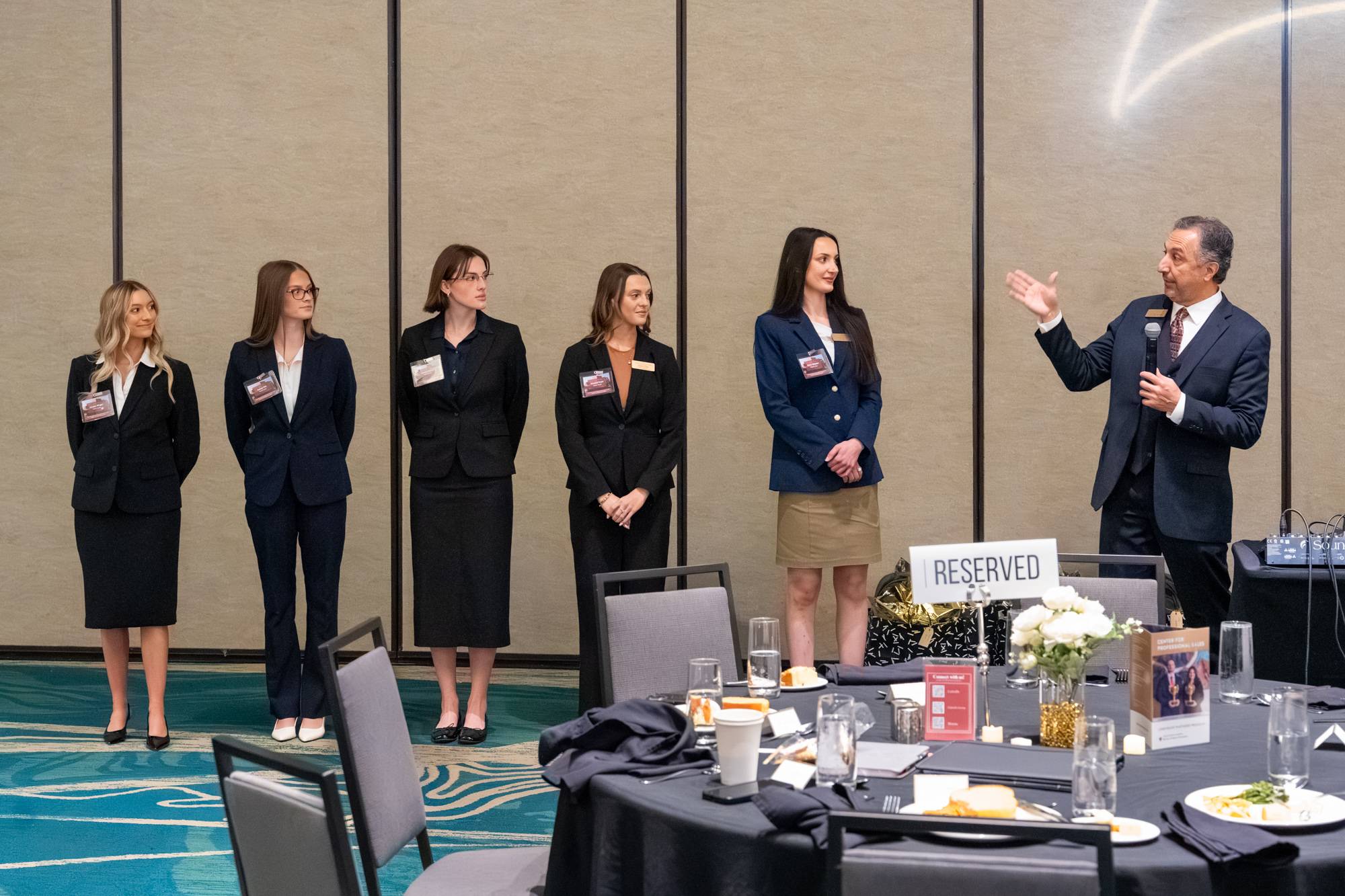 Five sales team students standing to the left of their coach