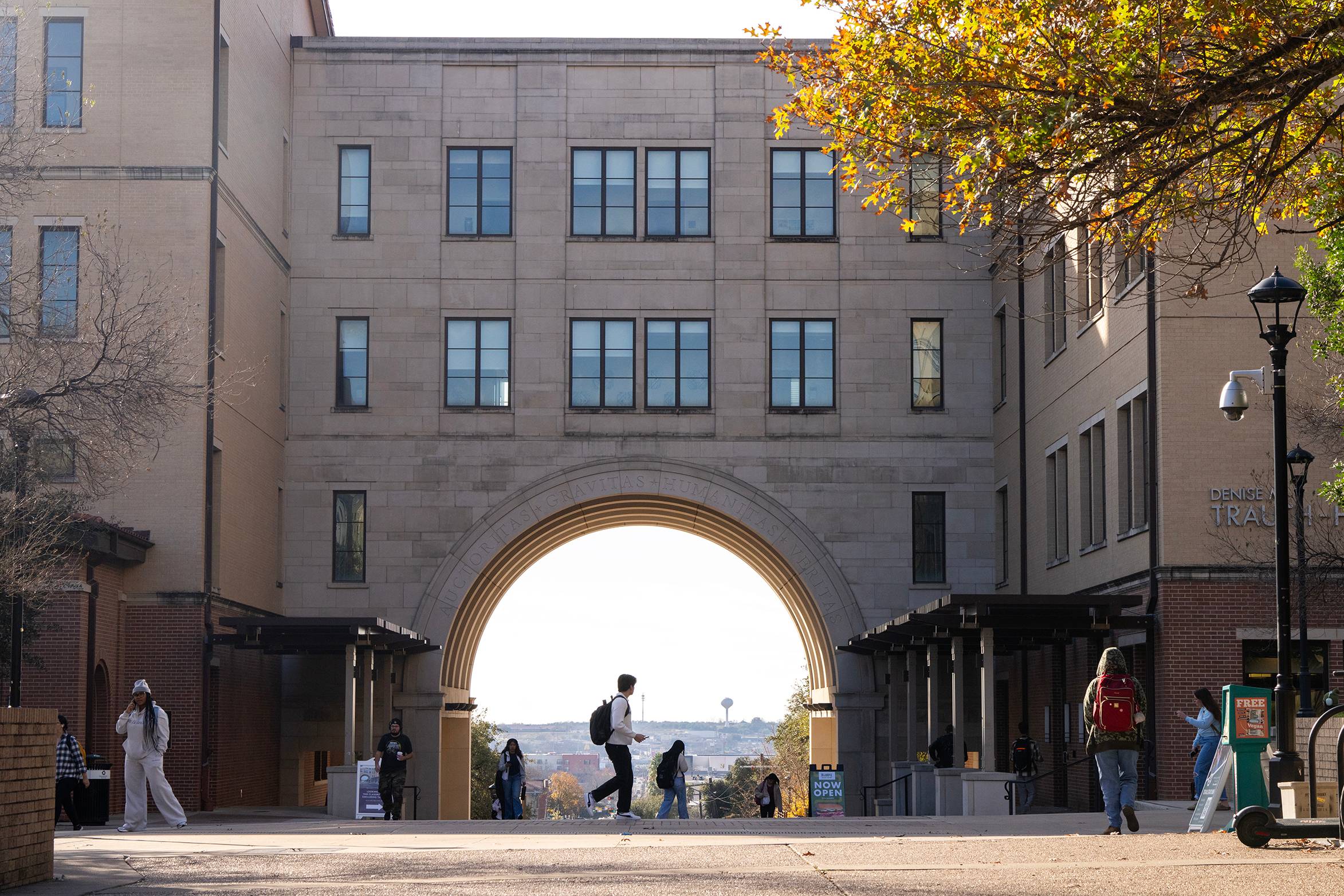 people walking on campus in front of large arched building