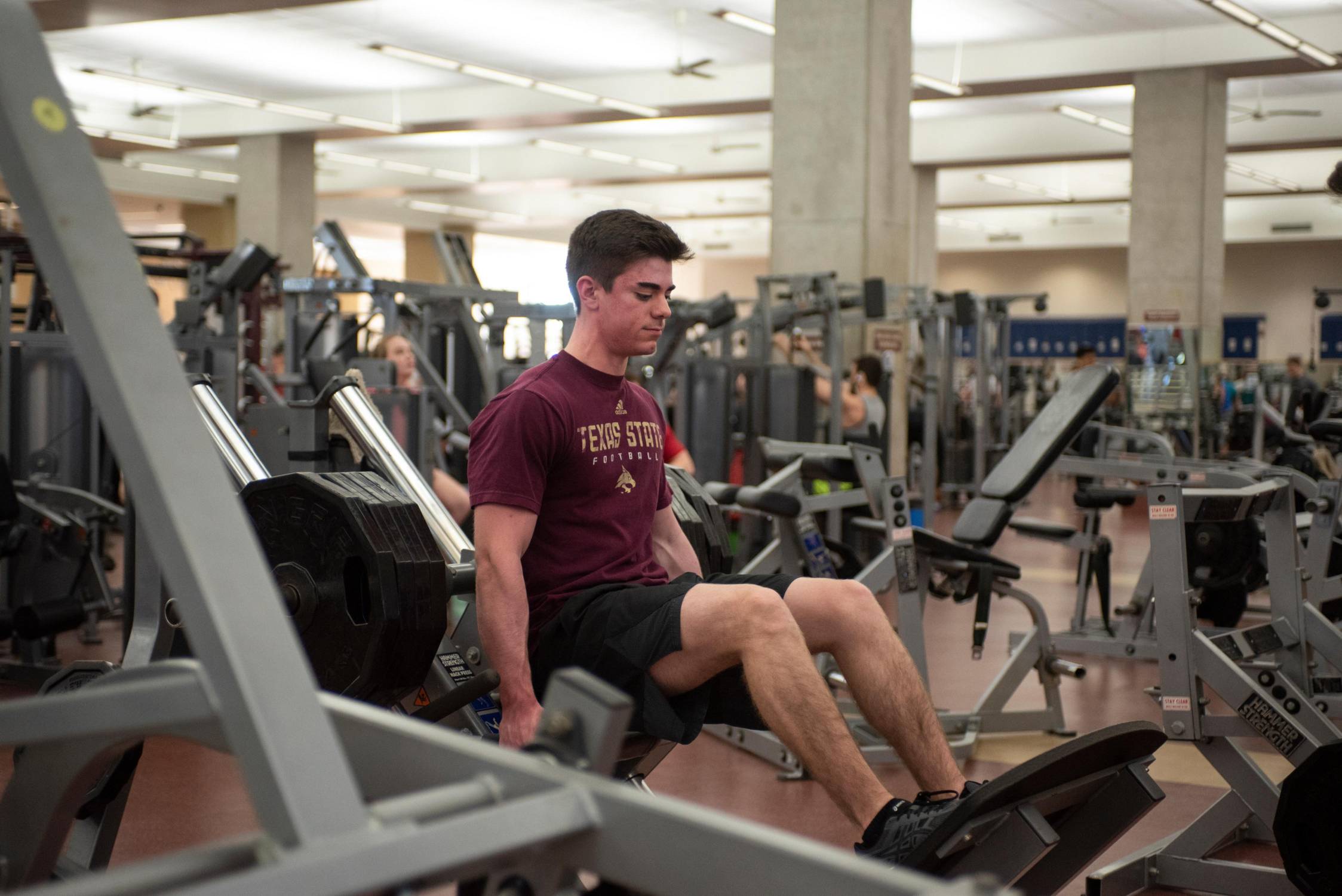 man lifting weights while sitting on gym equipment
