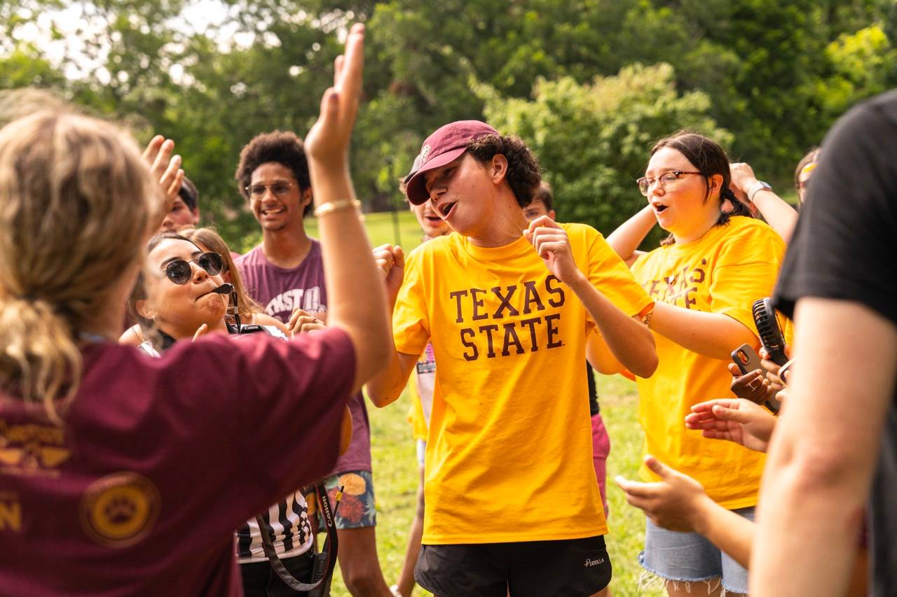 group of students cheer on another student dancing
