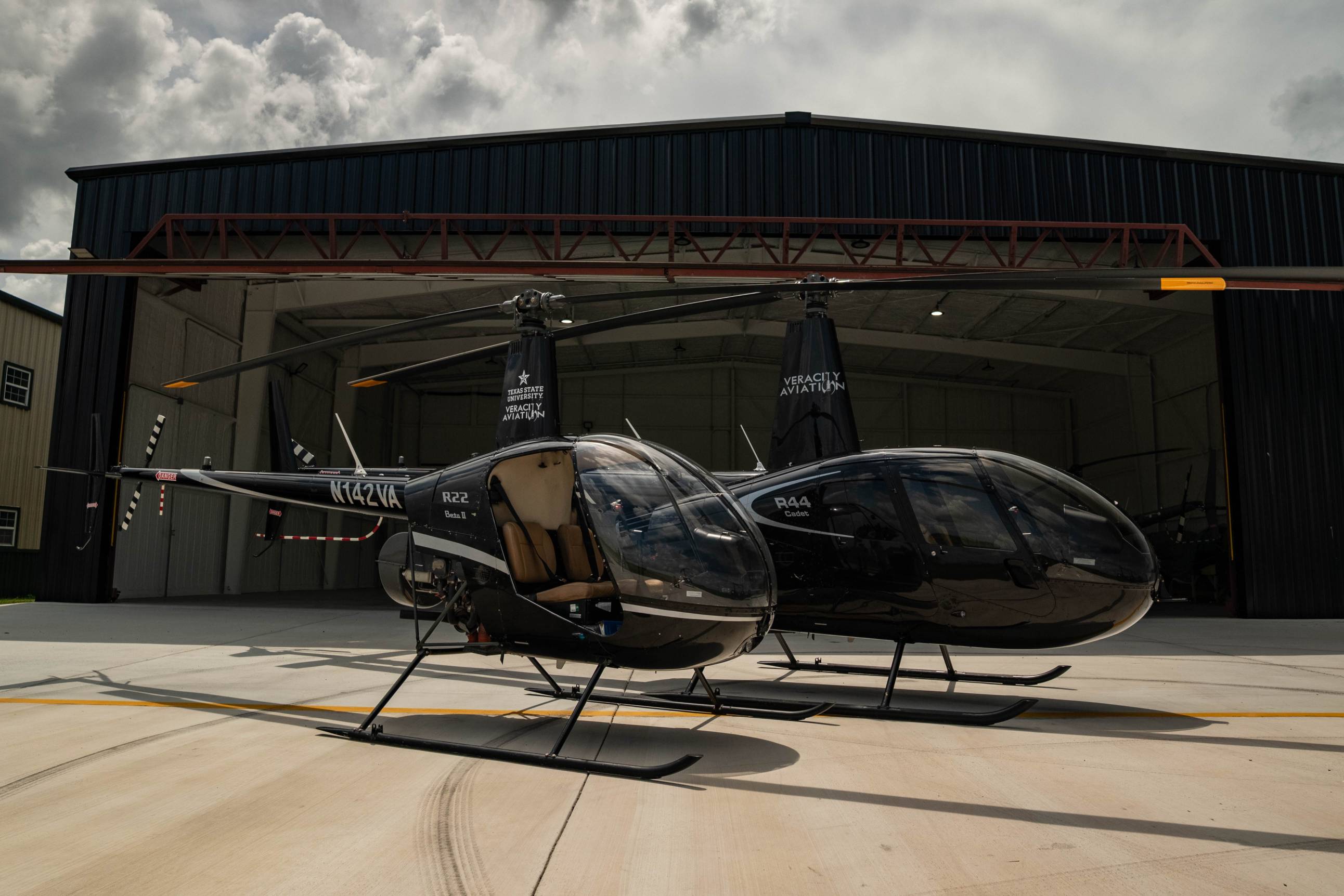 two helicopter in front of large hangar
