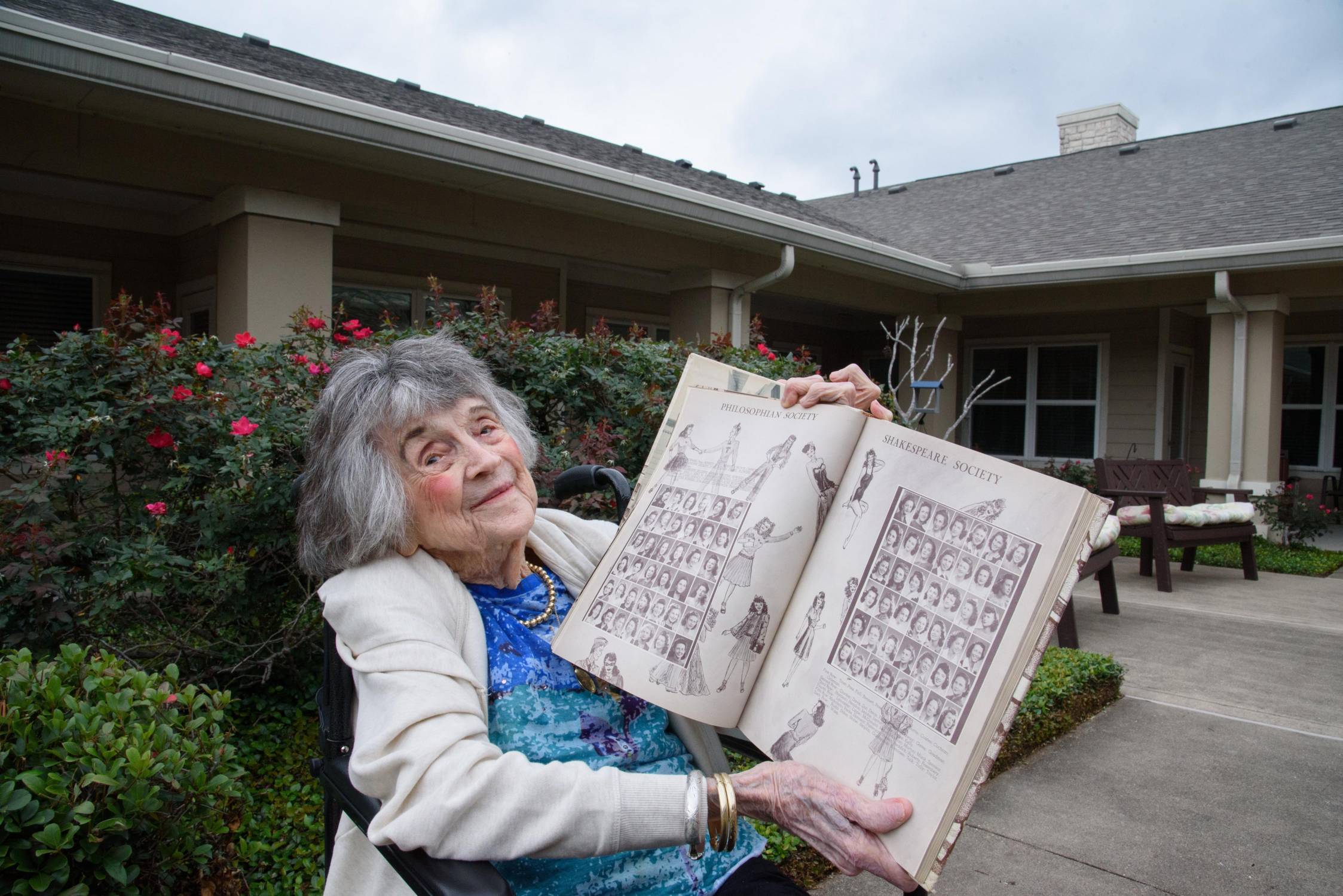 woman in wheelchair holds up yearbook from the 1940s