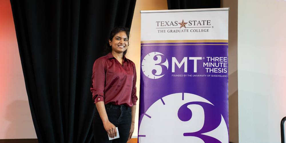 Heshini Weerakkody standing next to a 3MT sign with her arms crossed