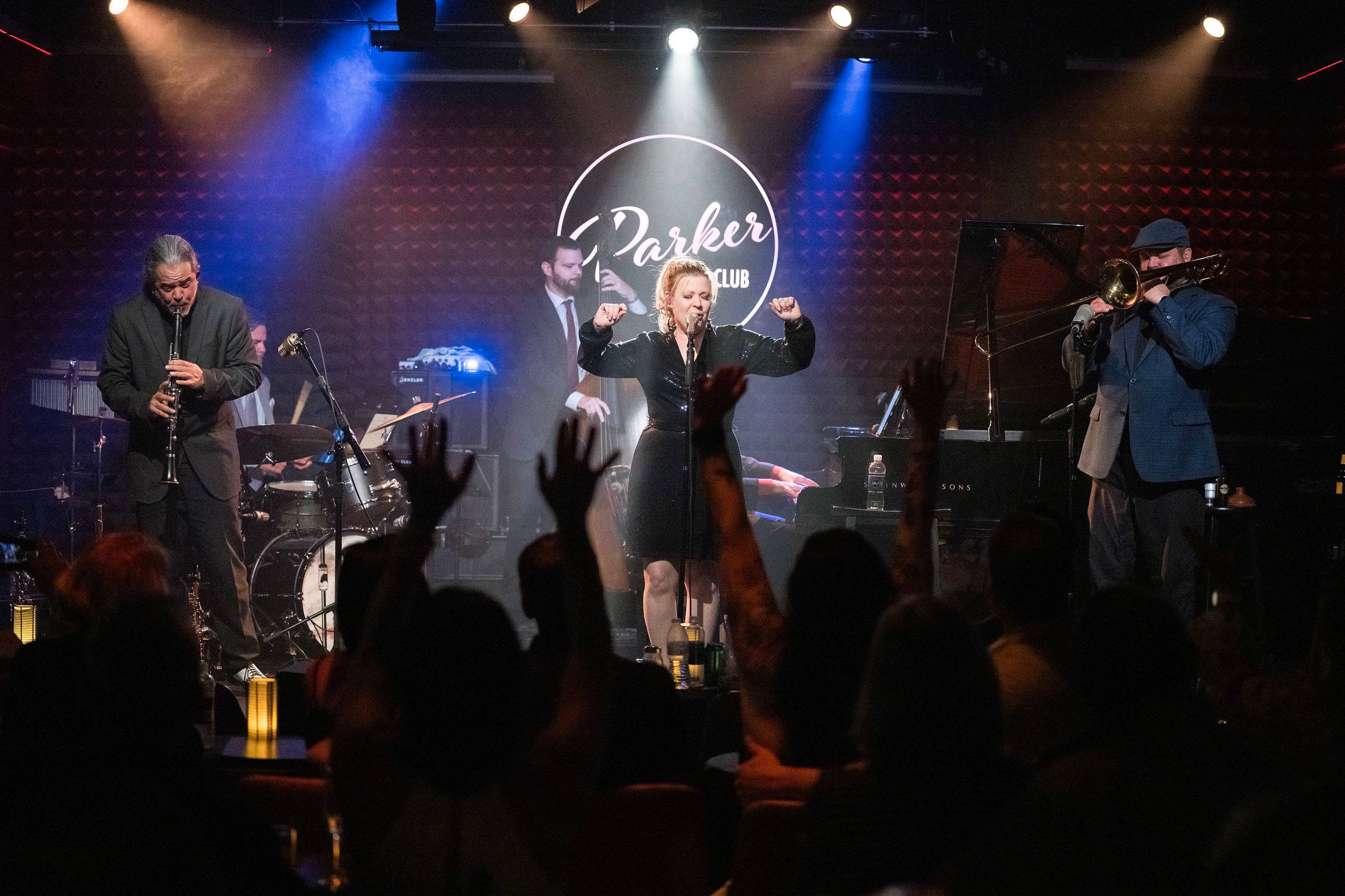 Musicians on stage perform with a singer in the center