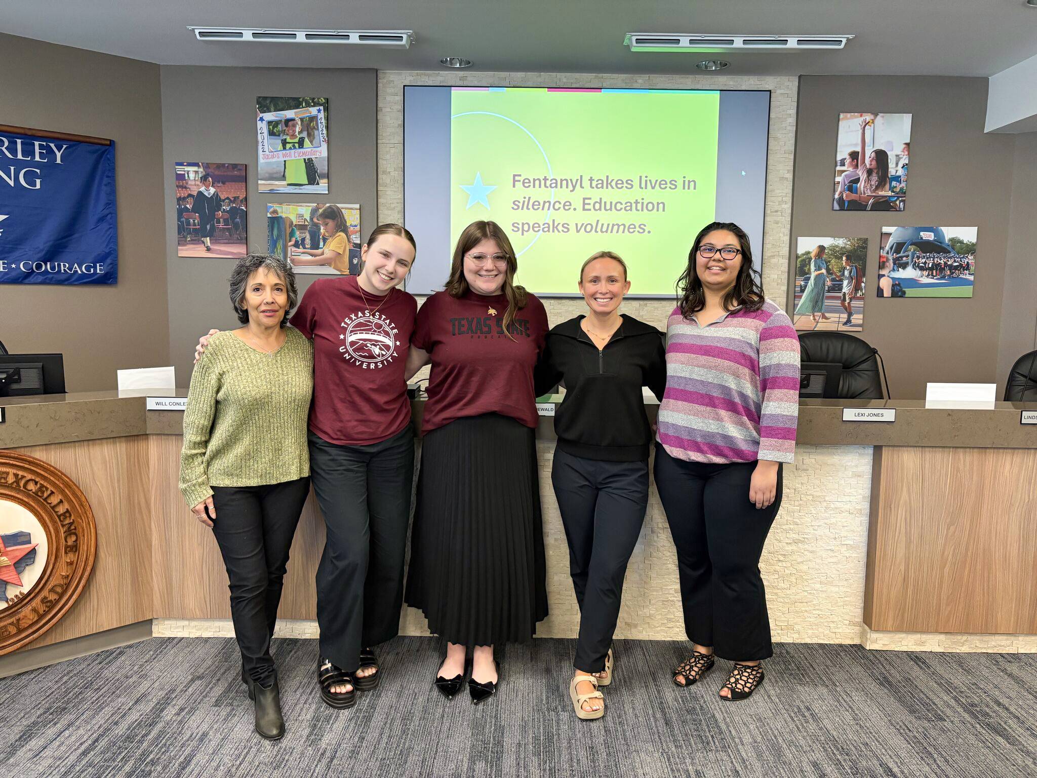 five woman pose for photo in front of presentation