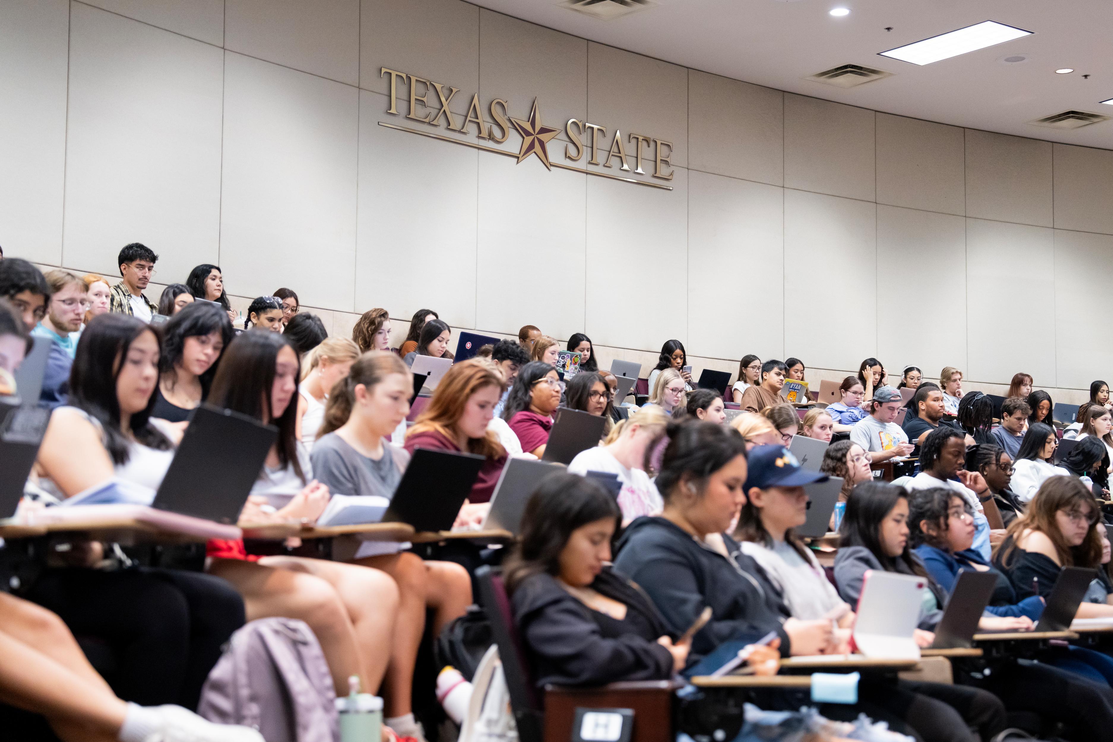 large auditorium of students listening to lecture