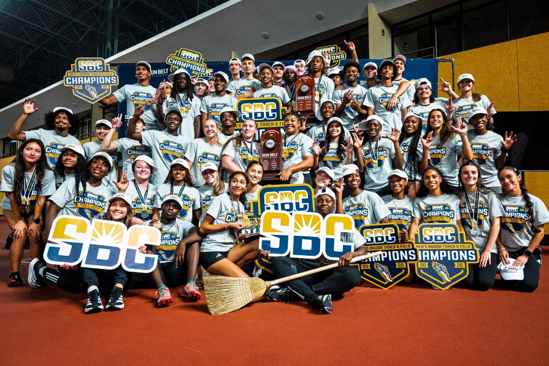Men and Women's Track & Field teams hold SBC championship signs