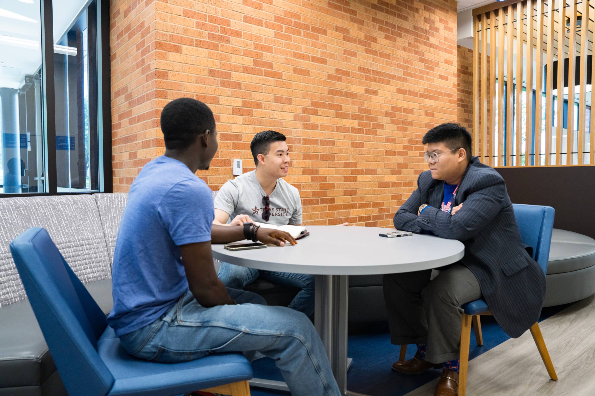 three students debate around a common area table