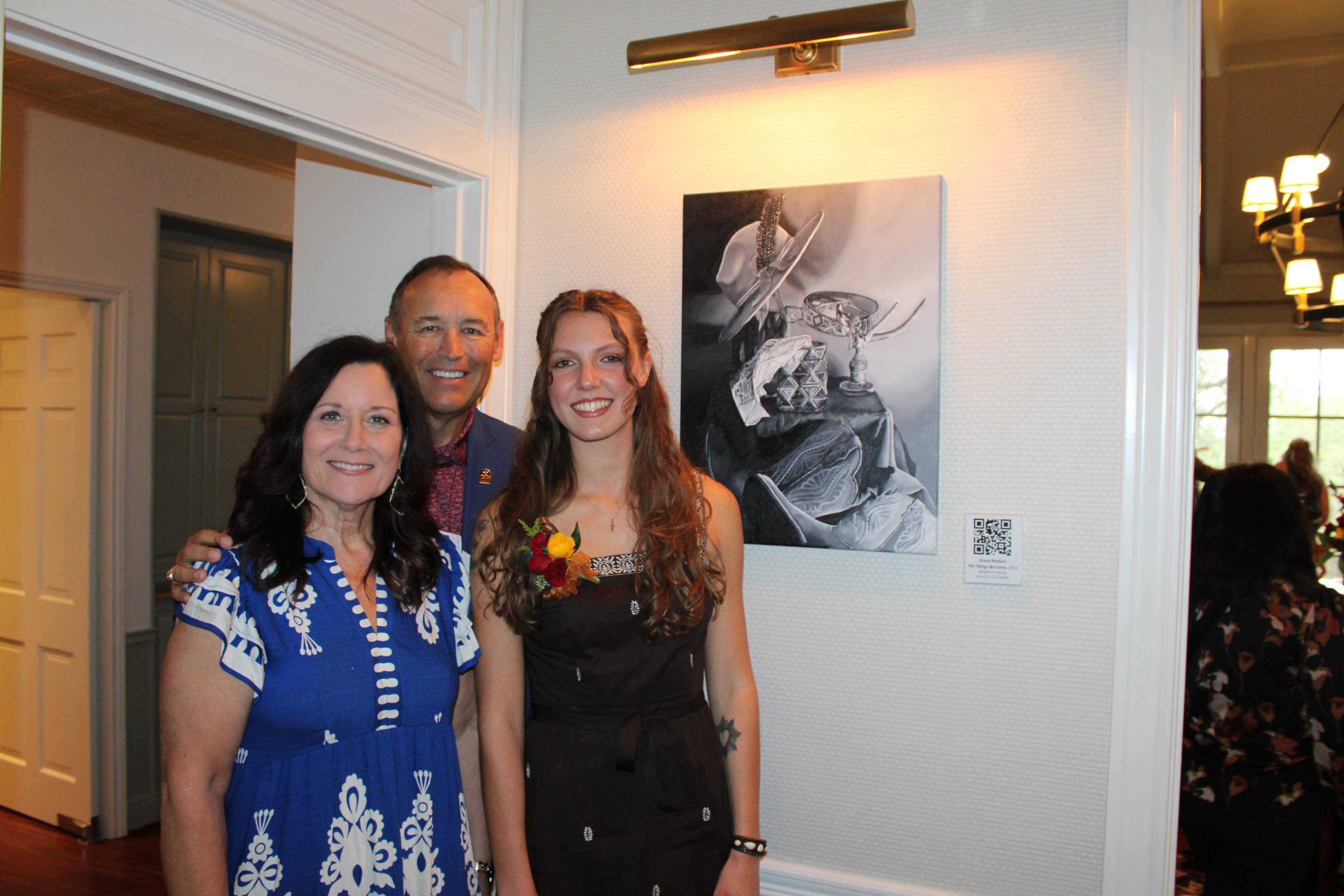 two women and a man stand next to a black and white painting