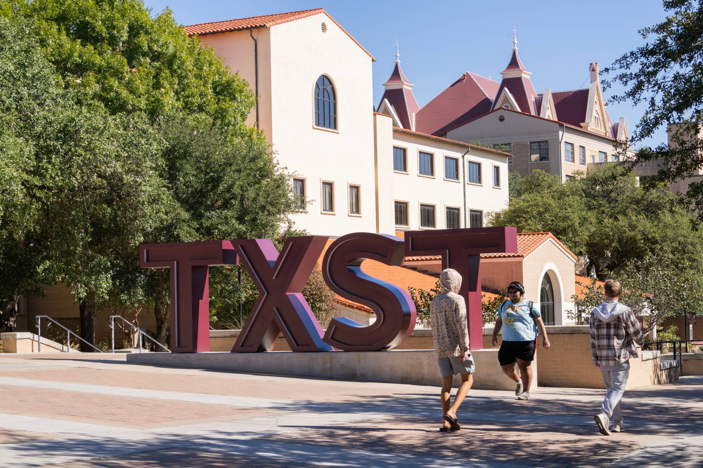 TXST Campus sign students walking around