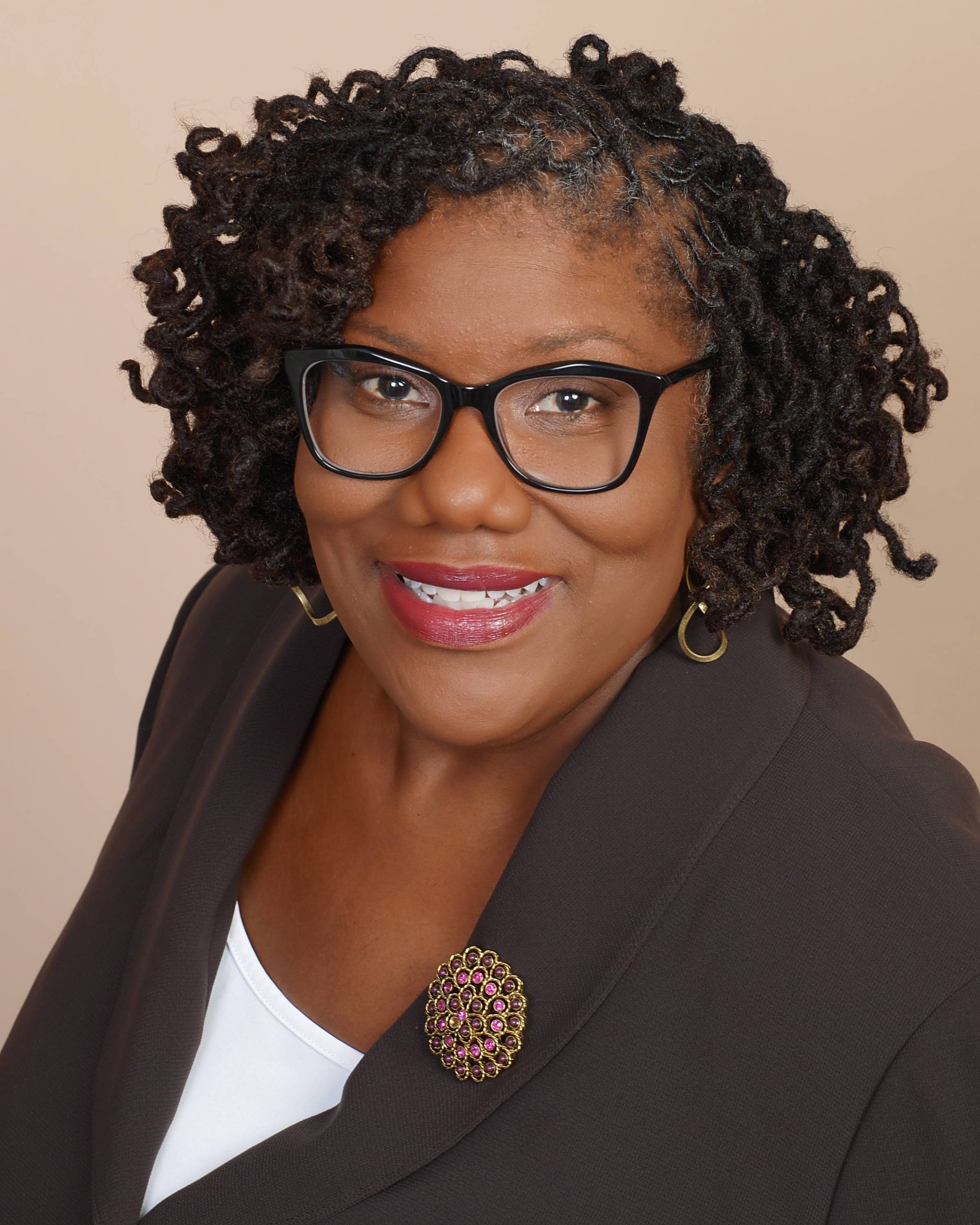 Valerie Holmes headshot wearing a blazer and brooch
