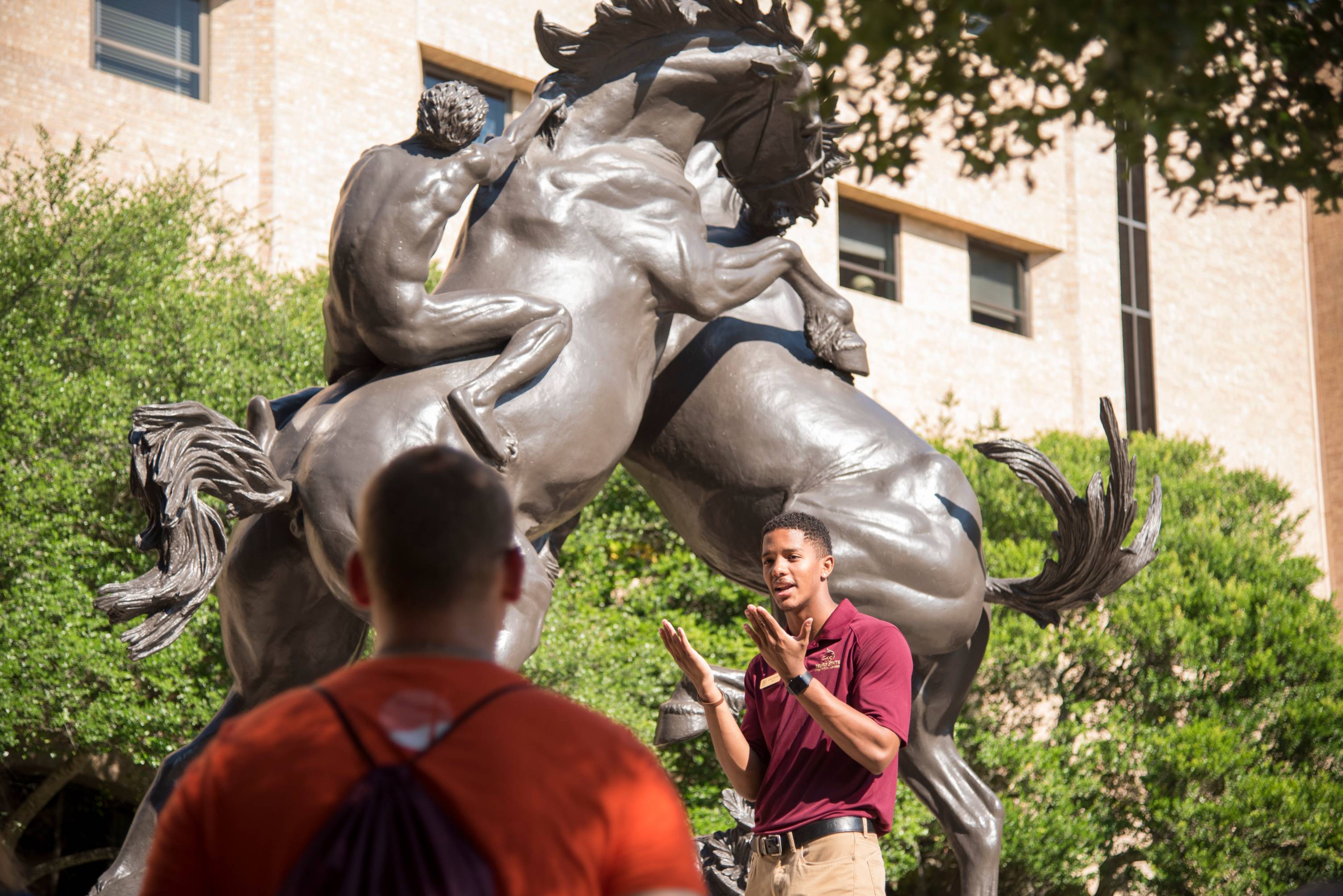 Bobcat stallion statue with tour guide in front speaking