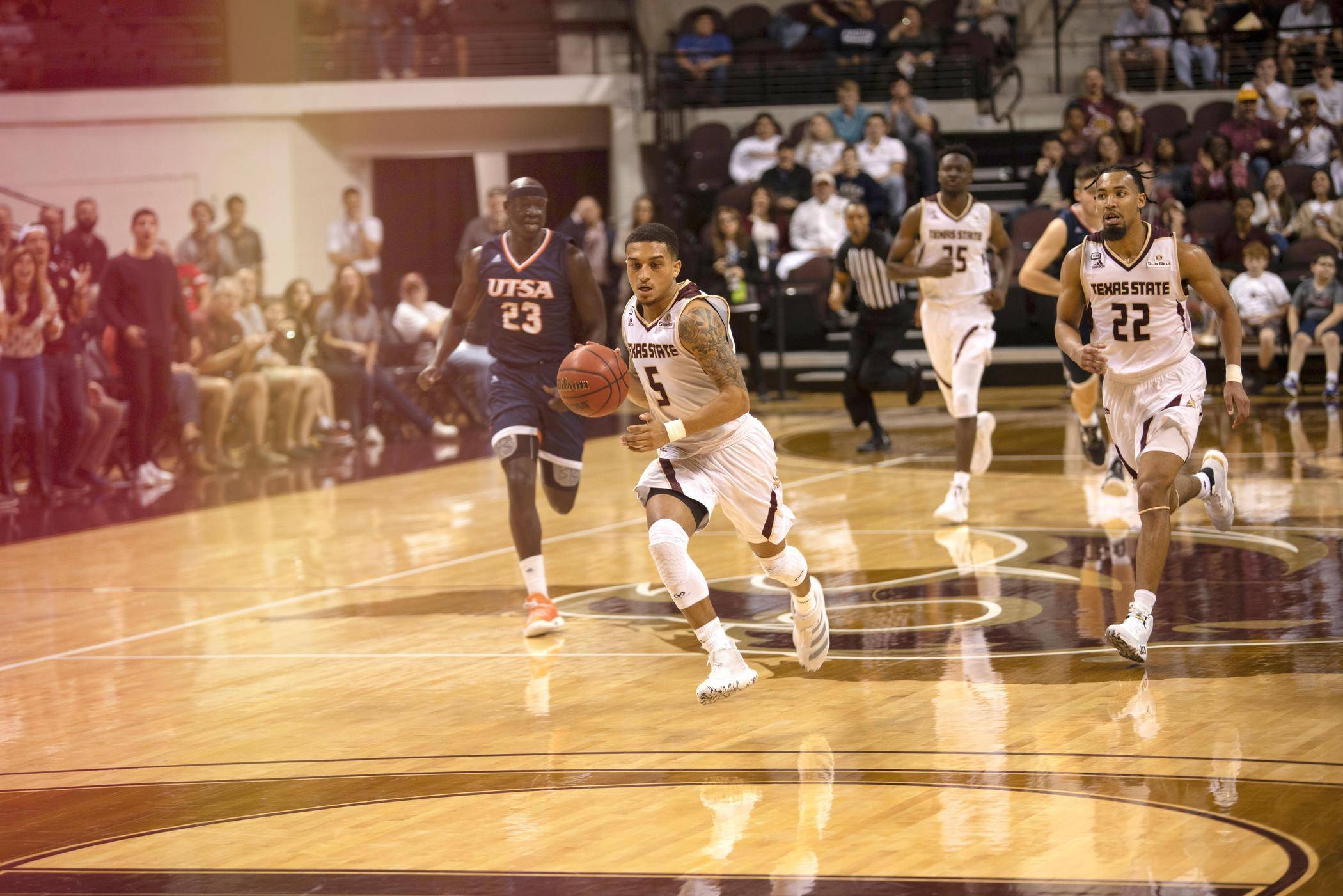 Bobcat basketball player drives down the court with the ball.