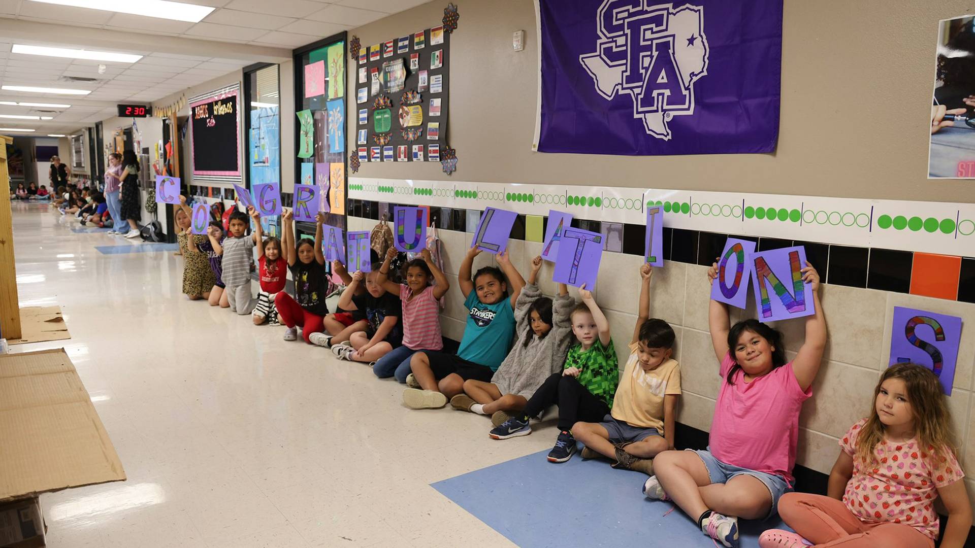 elementary school children holding up letters than read "congratulations" in school hallway