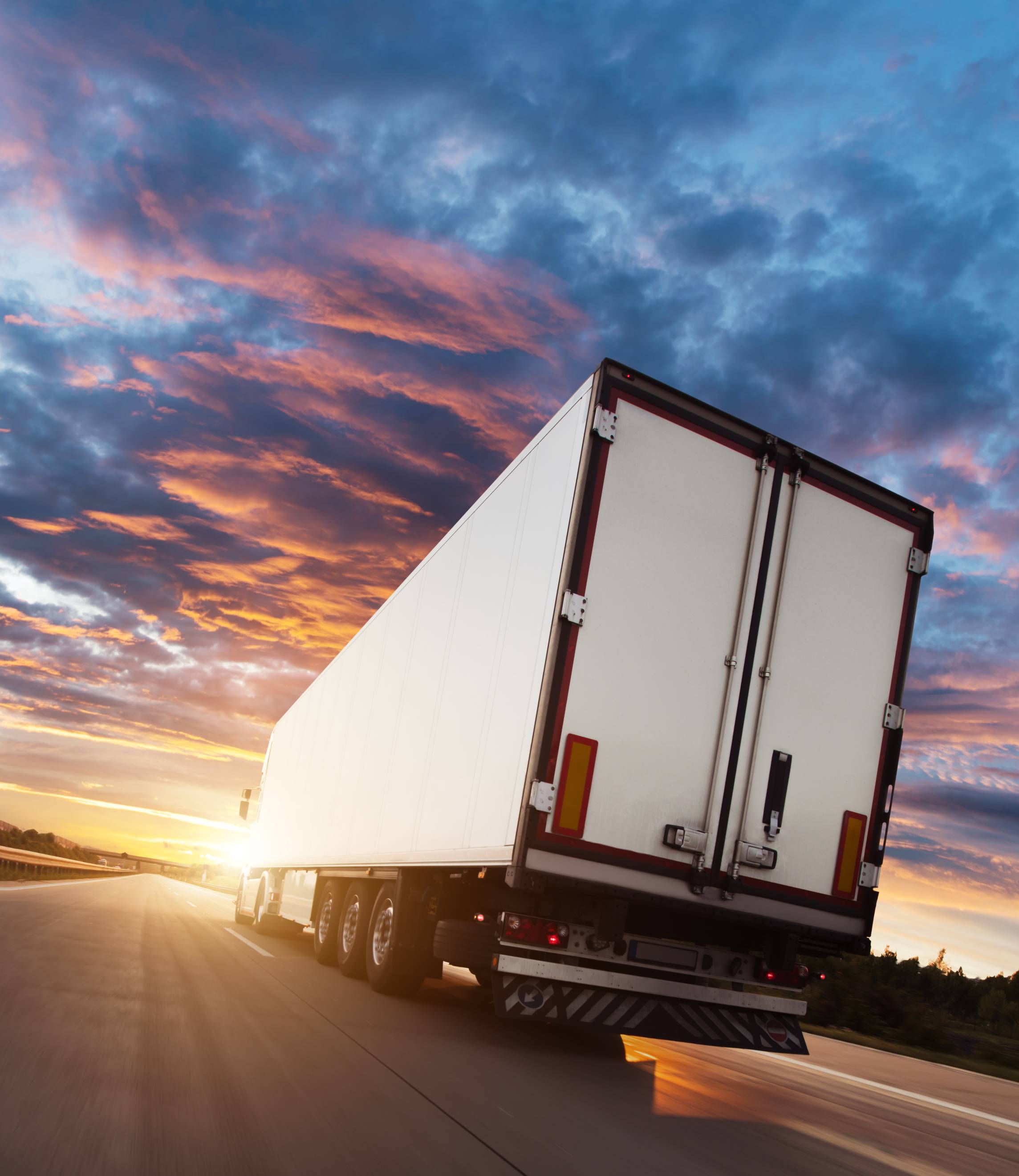 semi driving on the highway into the sunset