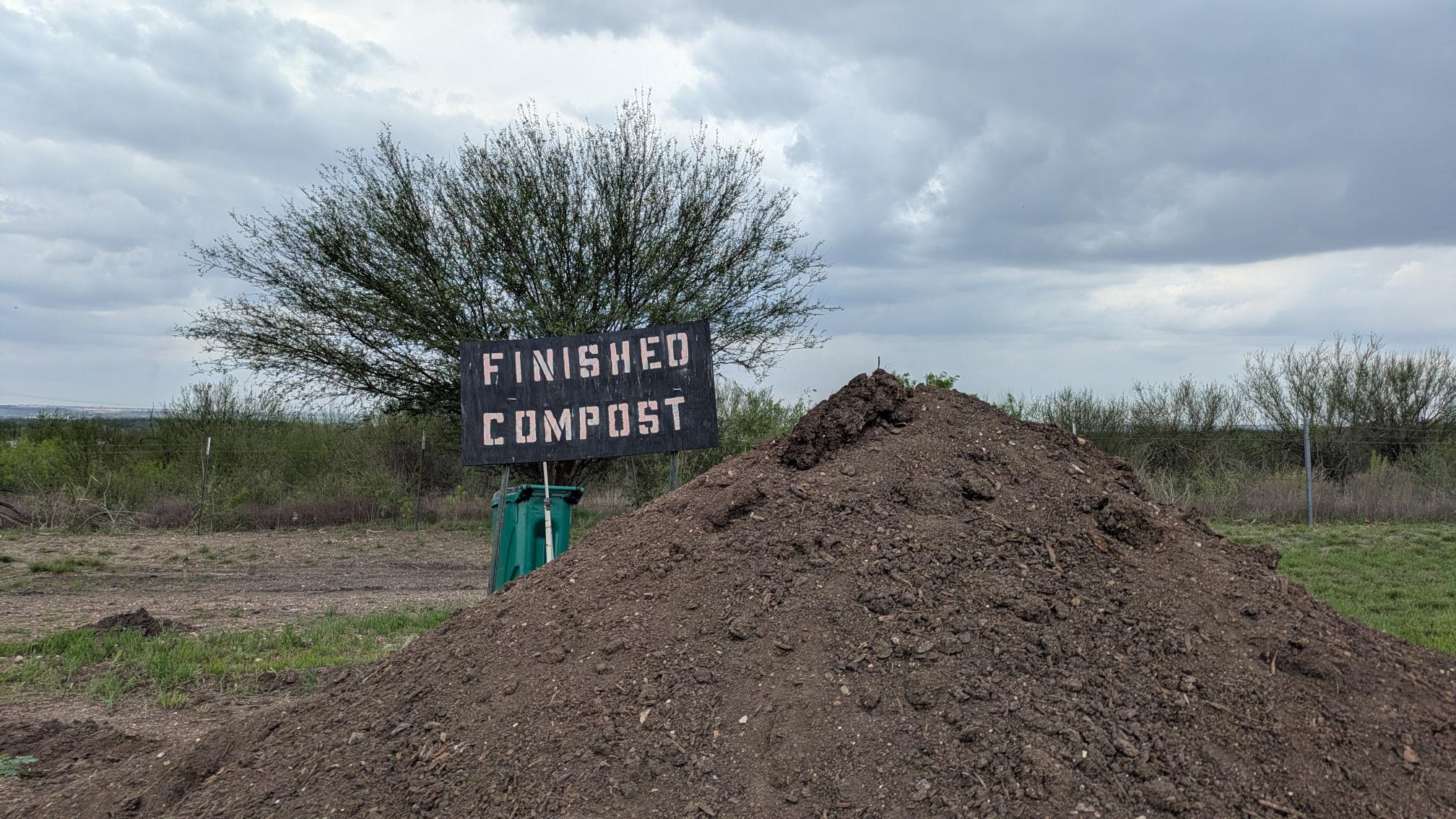 a pile of brown compost with a sign saying "finished compost"