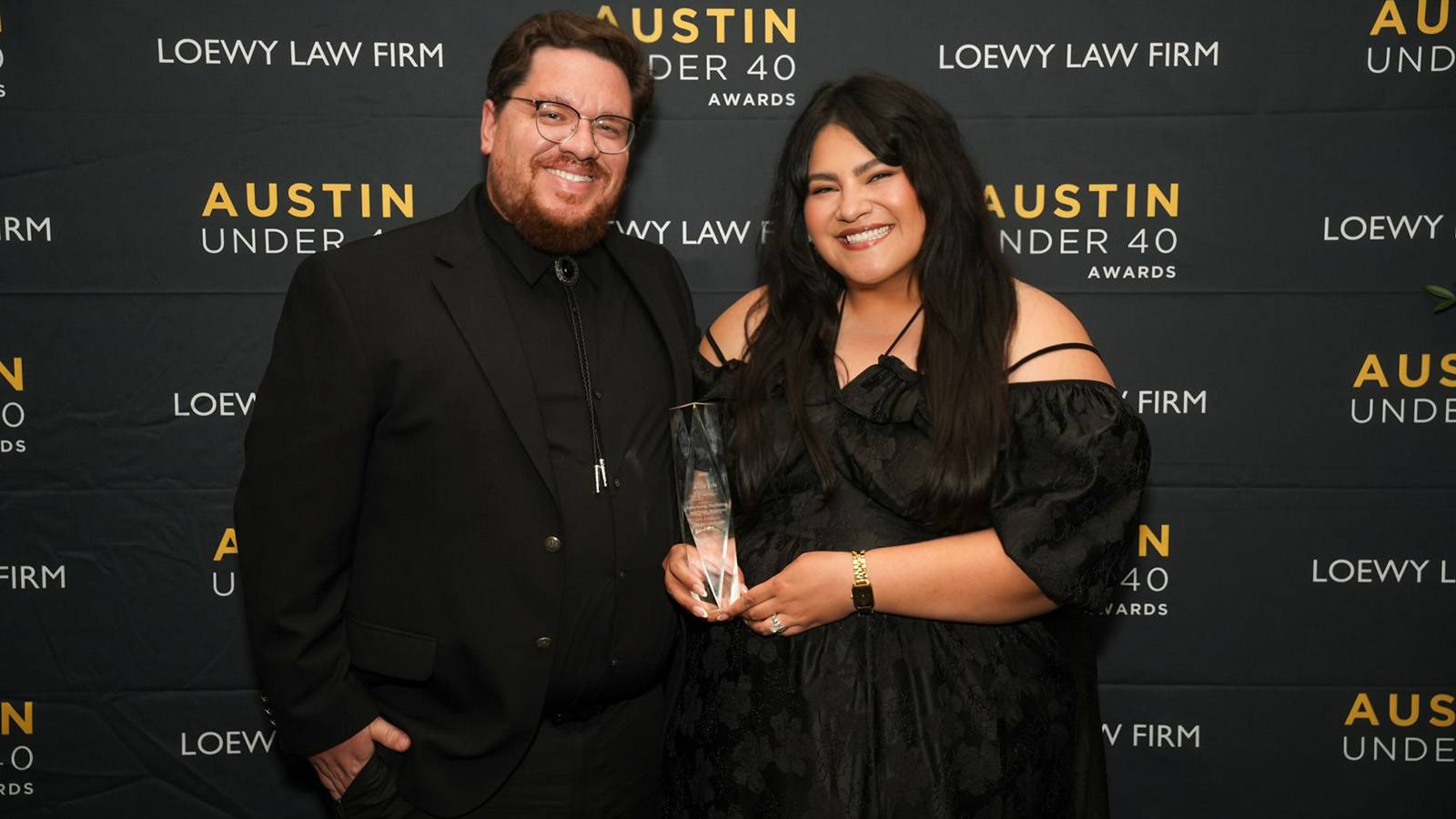a man and a woman smiling and posing for photos as the woman holds an award