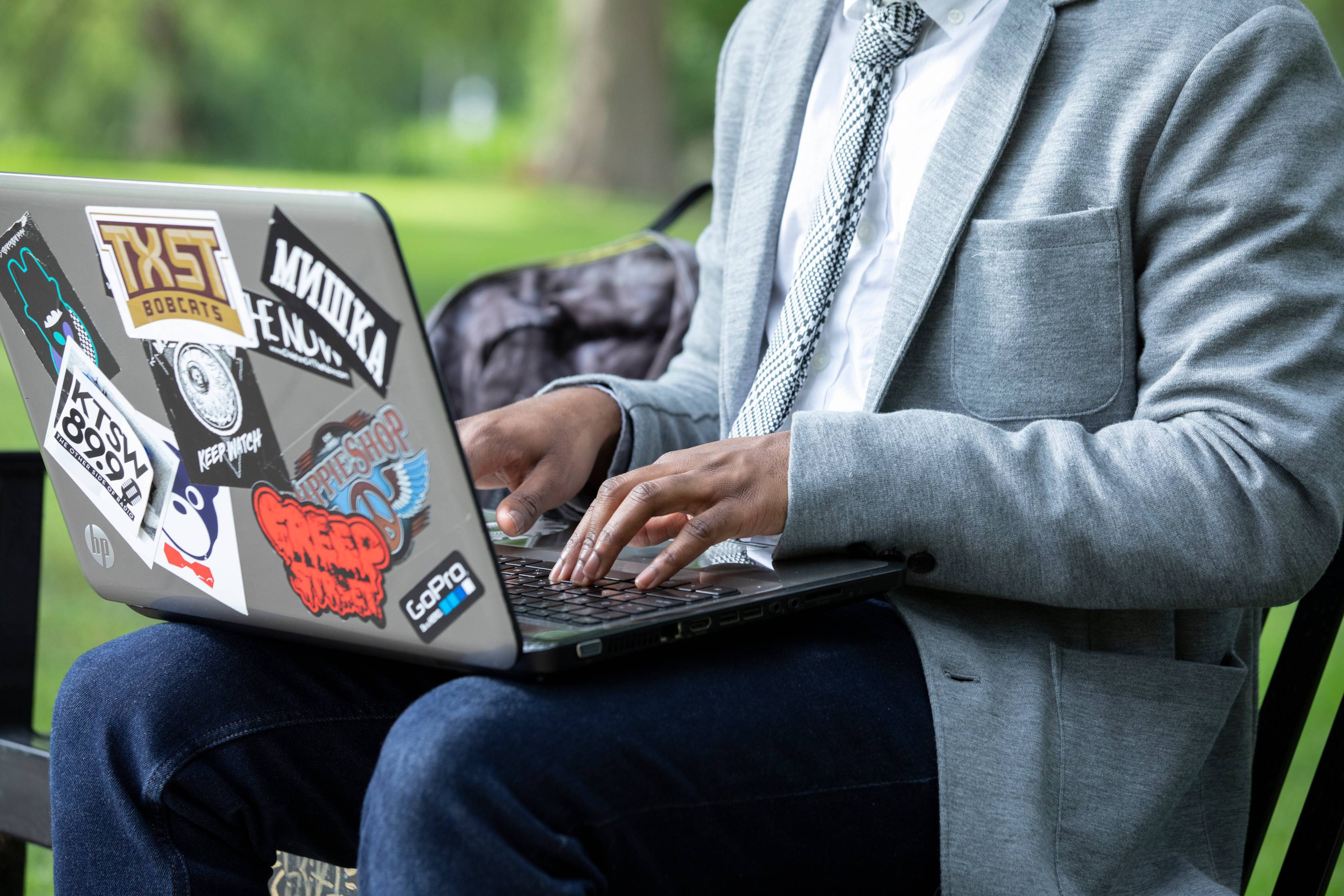 Student in blazer types on sticker covered laptop