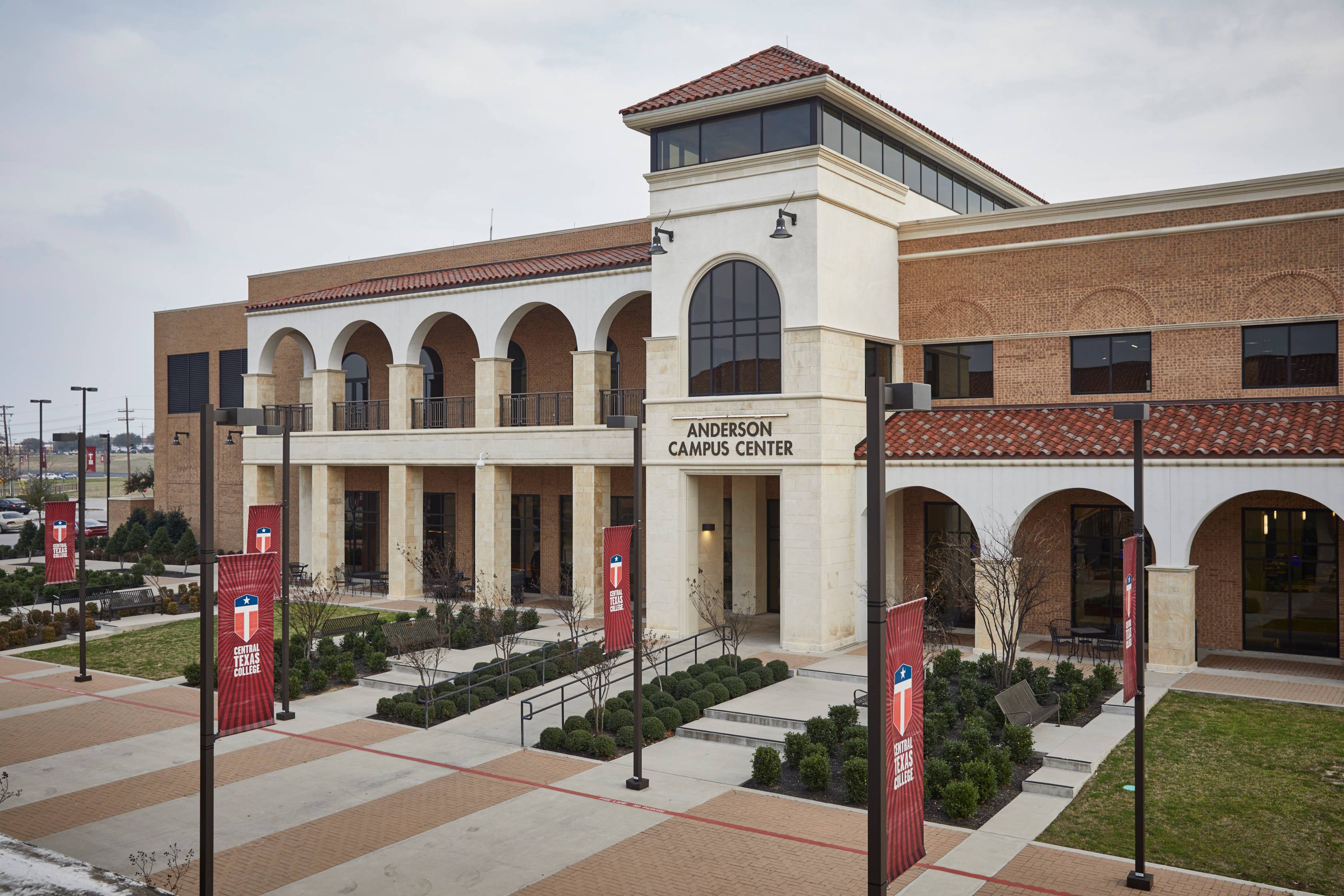 brick exterior of college campus with picnic tables and trees