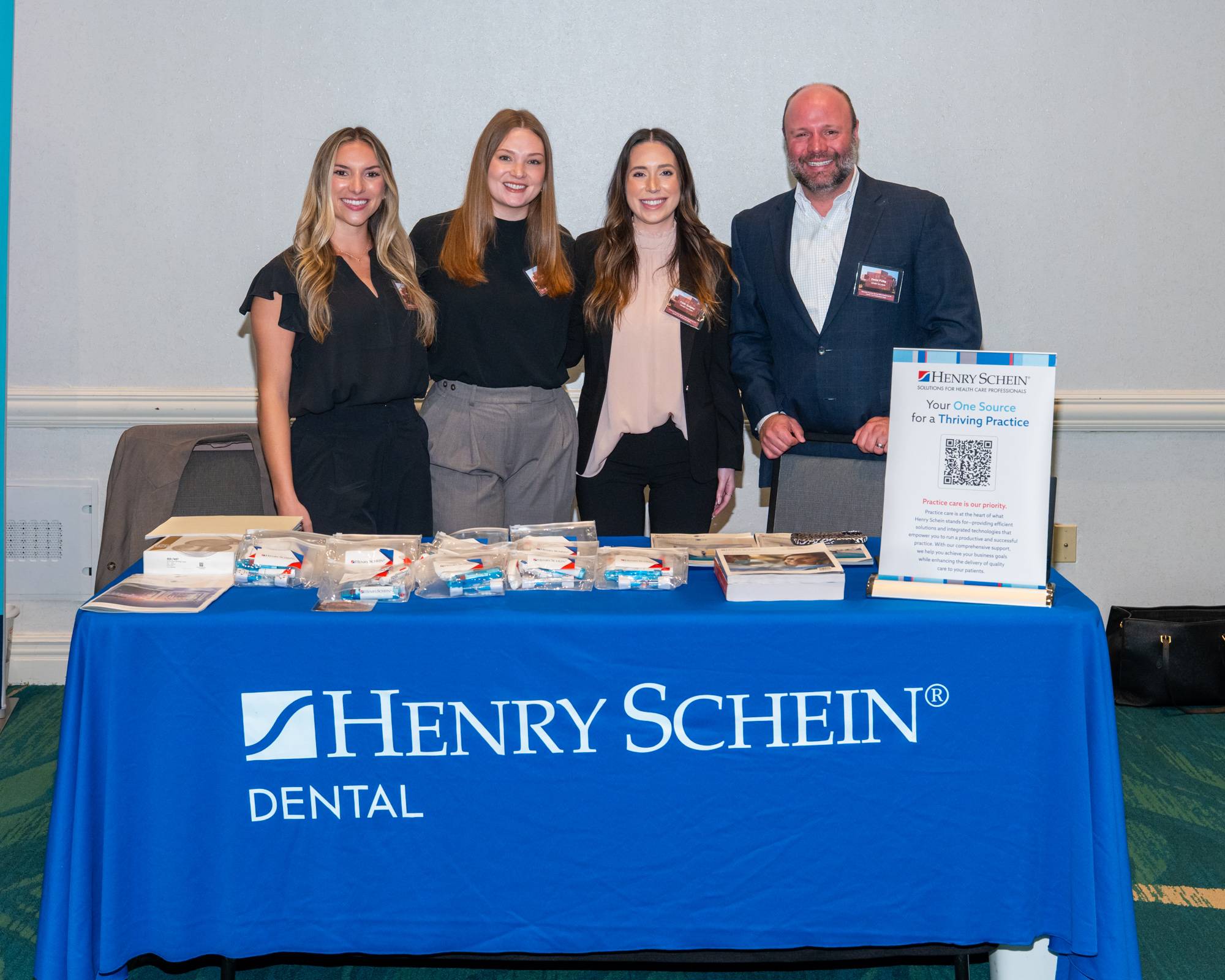 four people standing behind a blue table