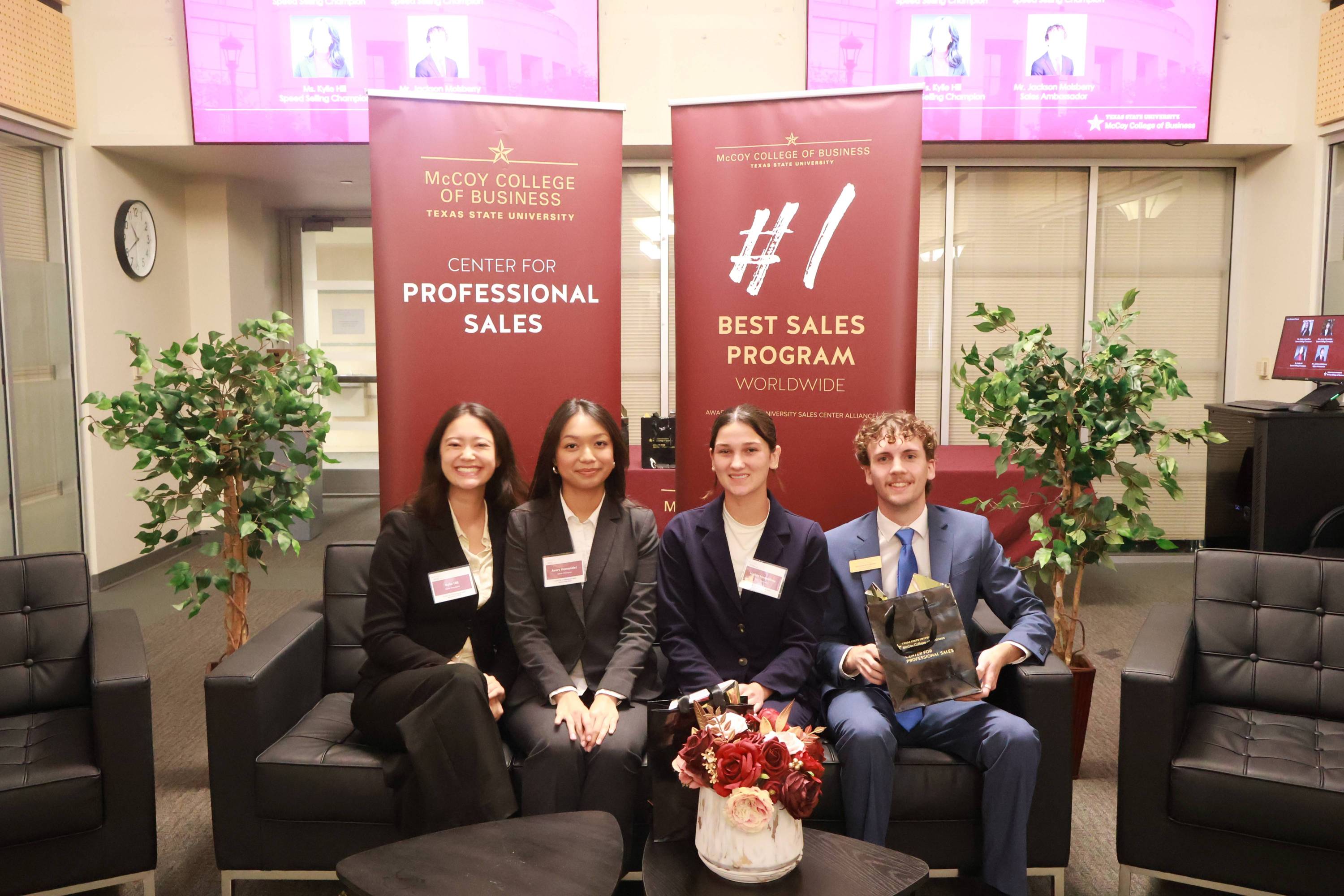 four students sitting on a couch in business professional