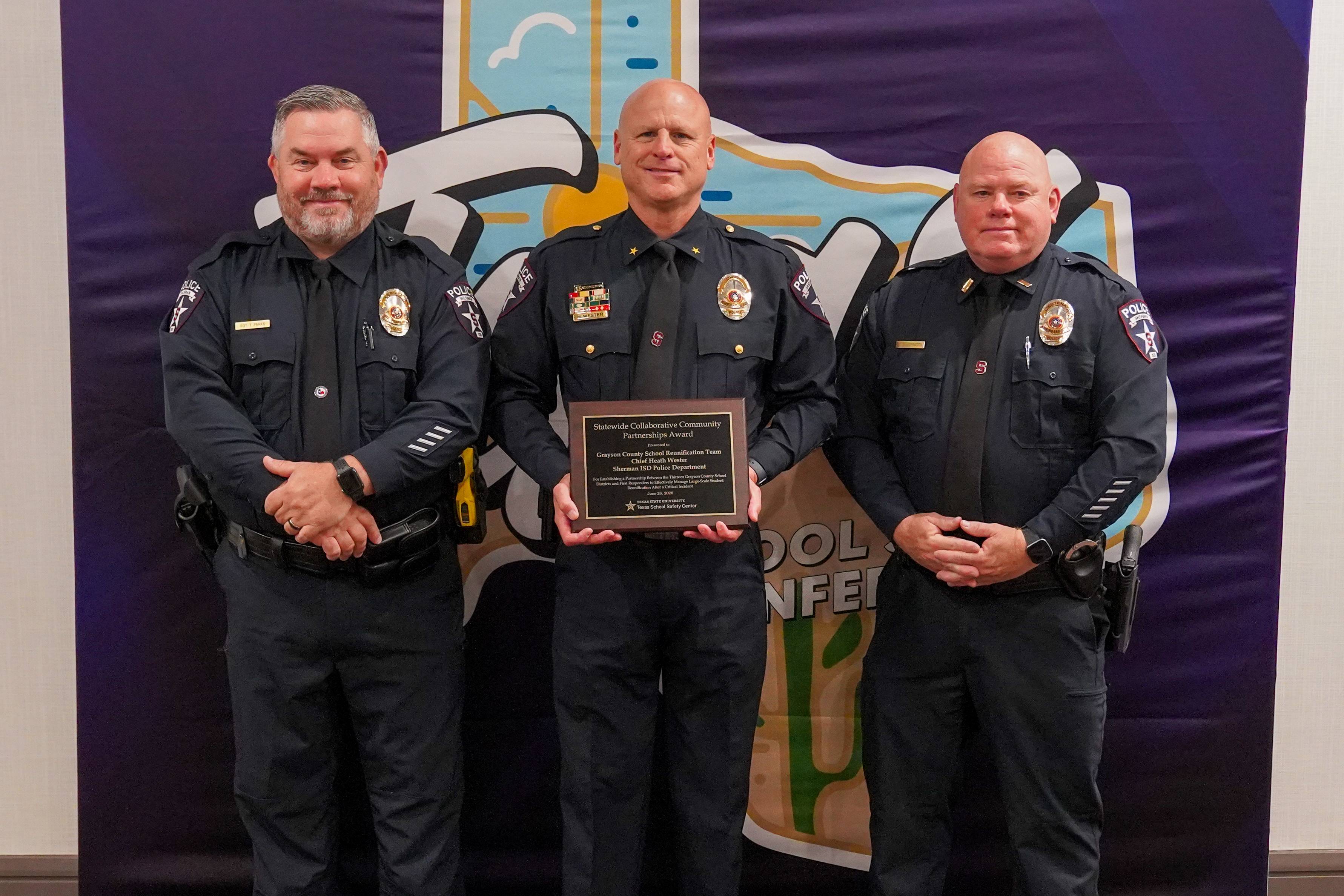 three men in police uniforms holding a plaque