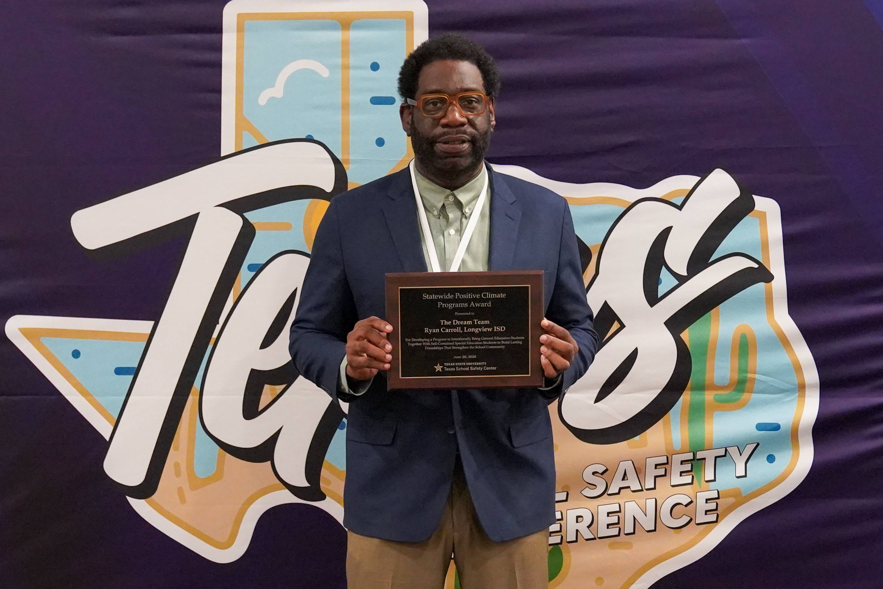man in business clothing holding an award plaque